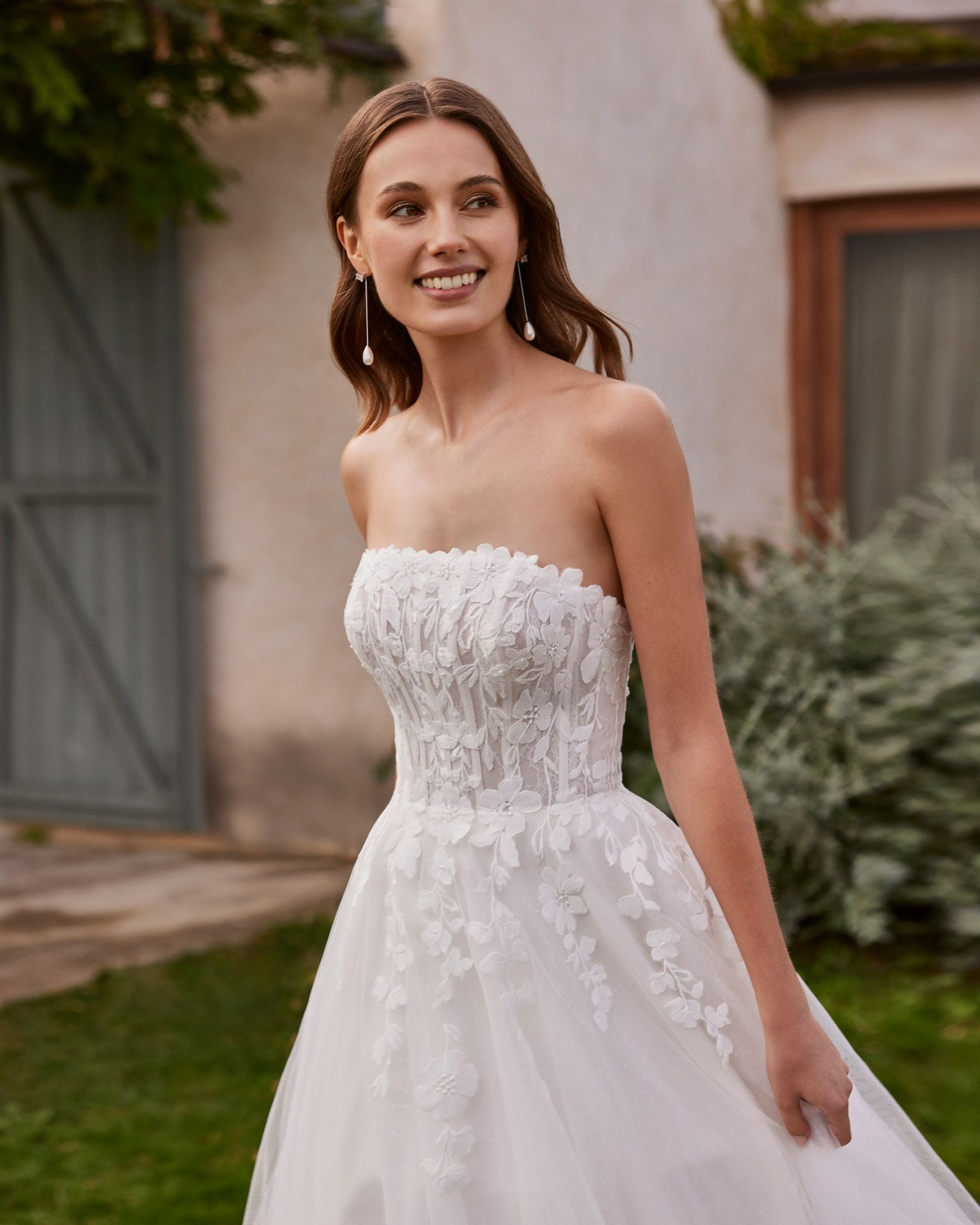 Eine Frau in einem weißen Brautkleid steht vor einem Gebäude.