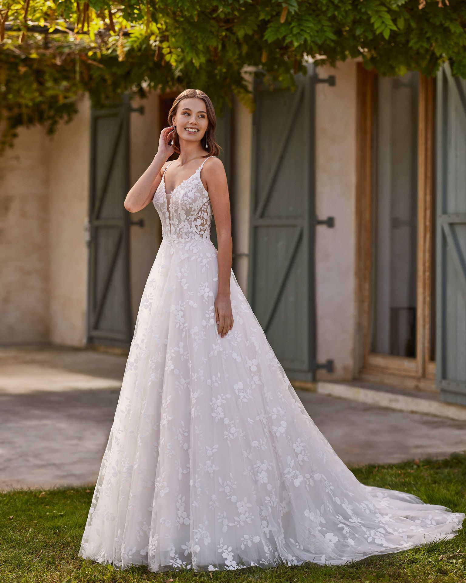 Langes Brautkleid mit A-Linien-Schnitt. Aus Spitze mit tiefem Ausschnitt, Trägern und offenem Rücken.