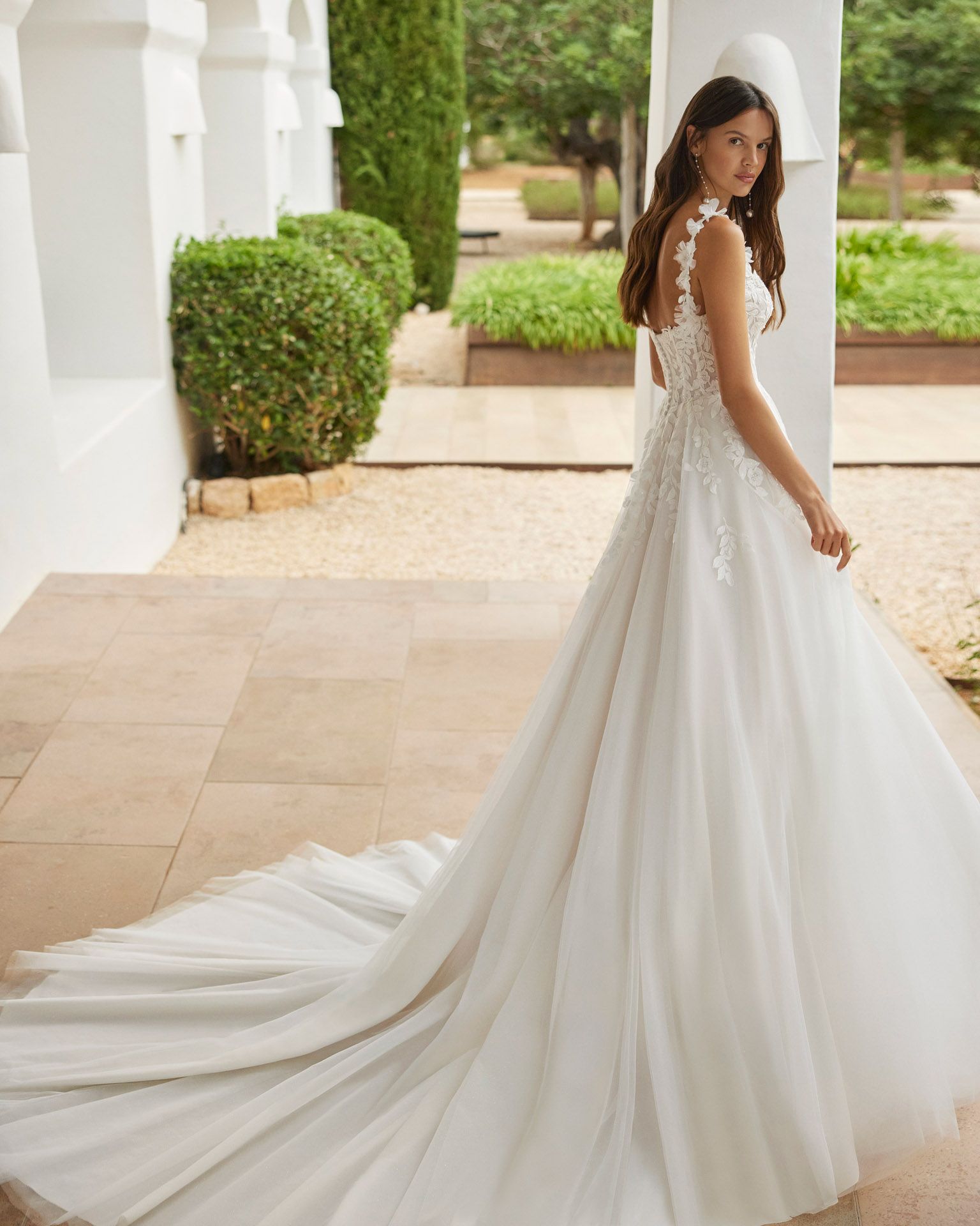 Eine Frau in einem weißen Brautkleid steht vor einem Brunnen.