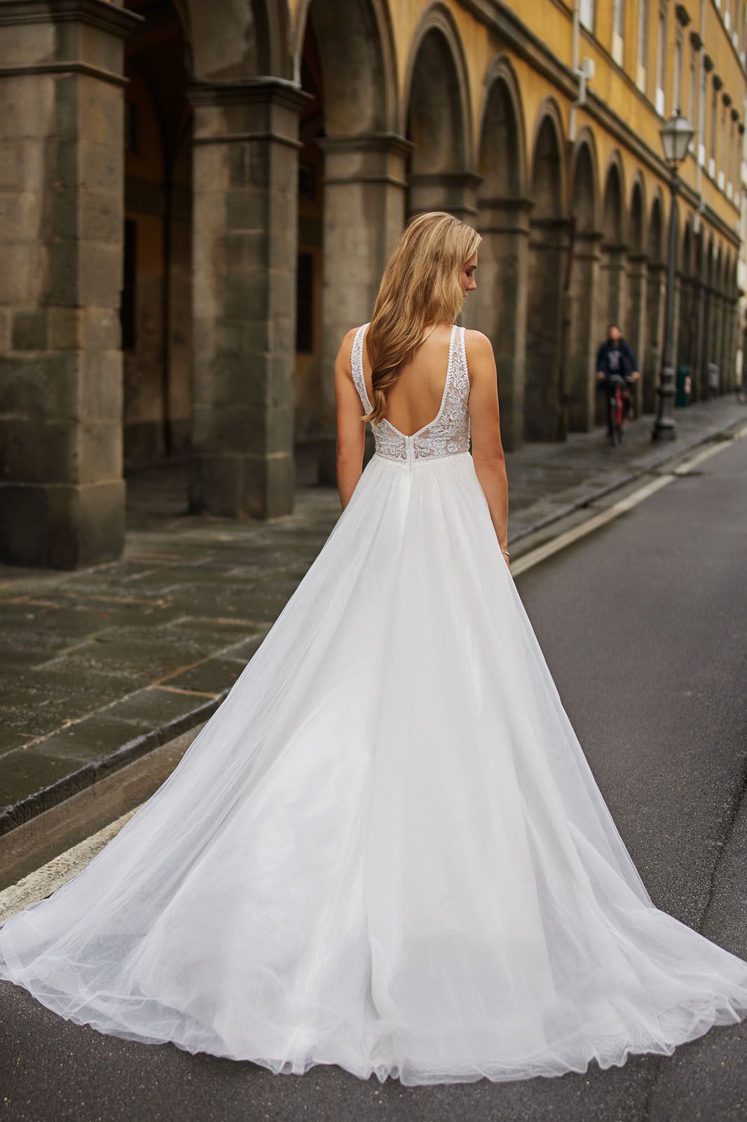 Eine Frau in einem Brautkleid steht vor einem Fenster.