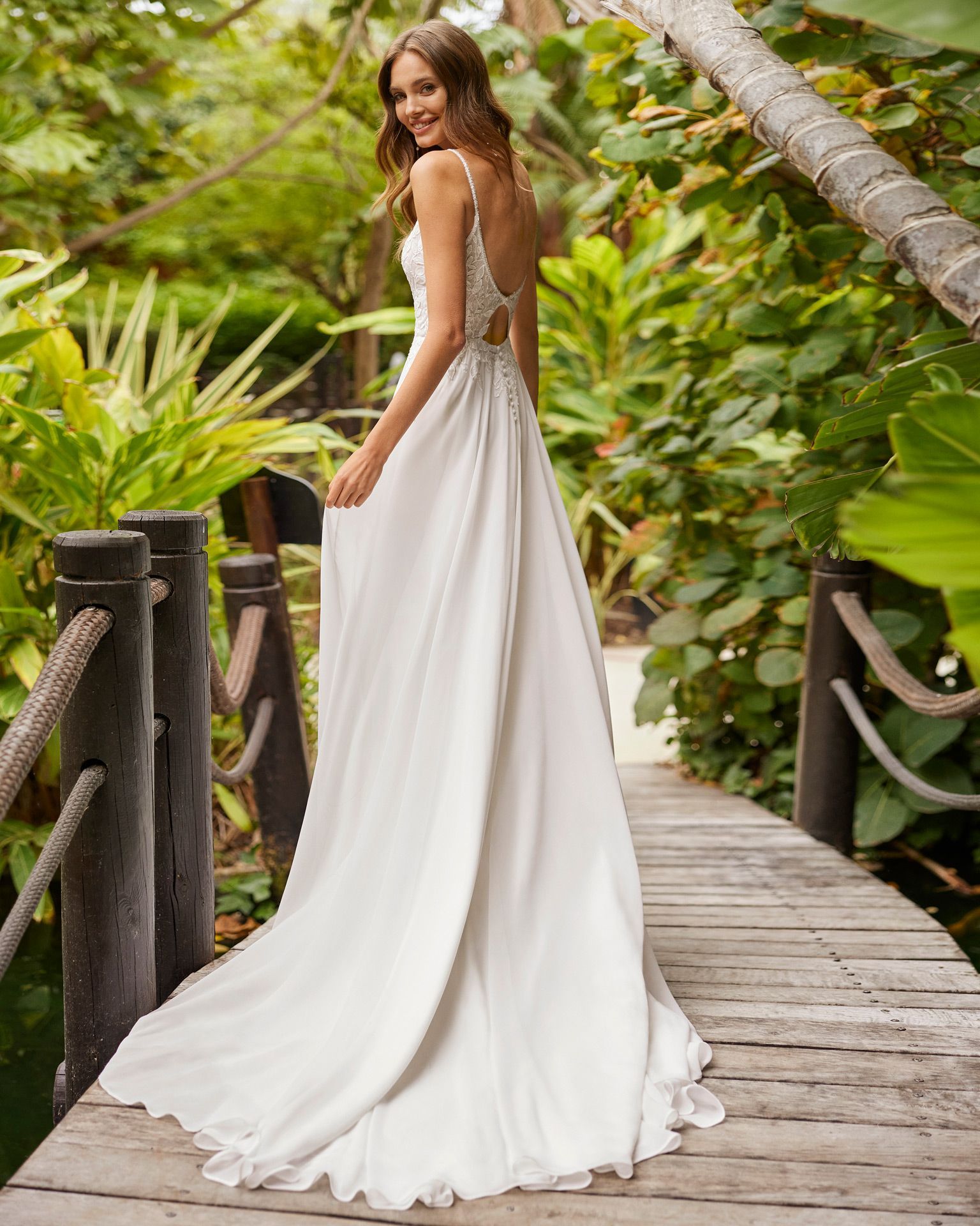Eine Frau trägt ein weißes Brautkleid mit langen Ärmeln.