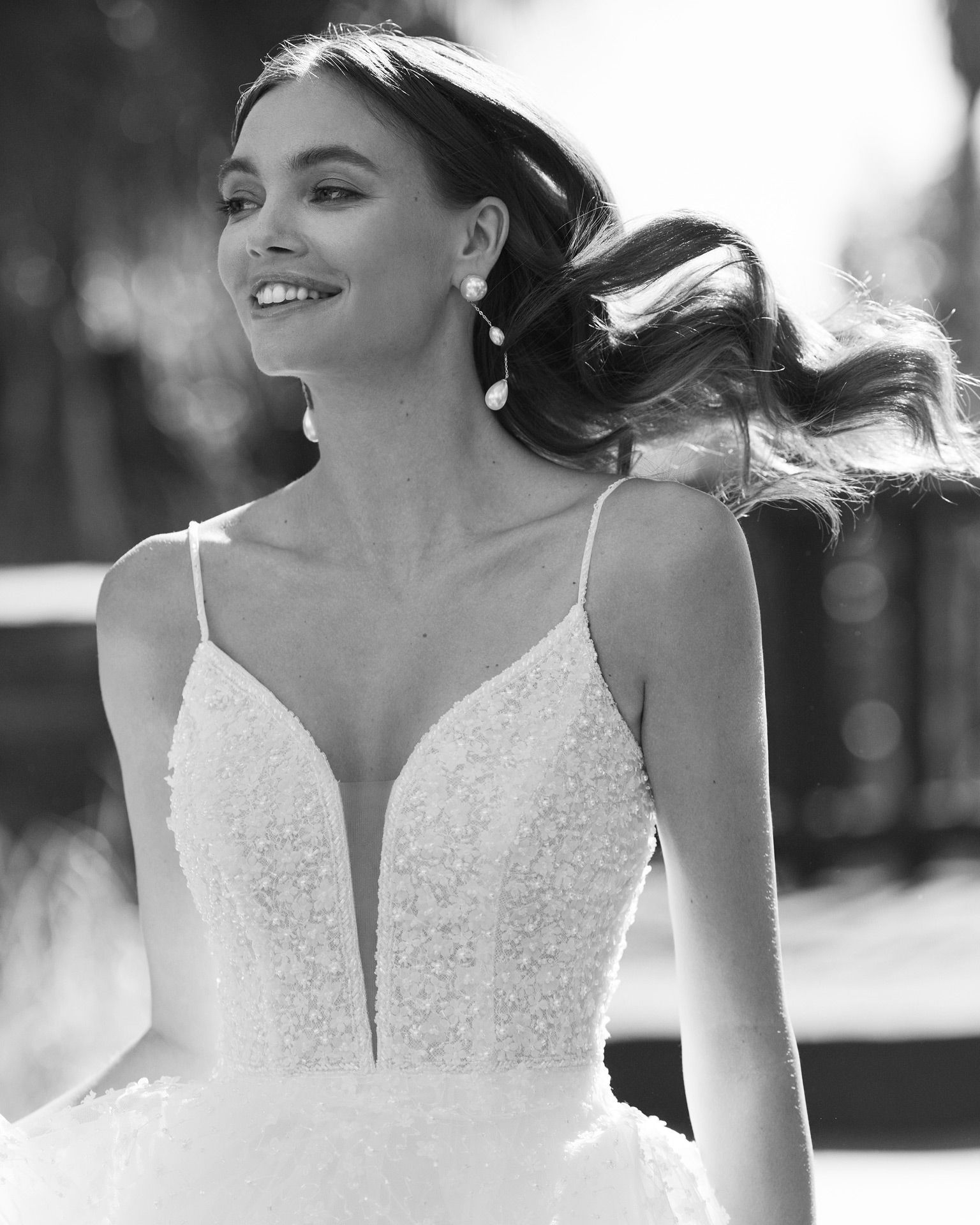Eine Frau in einem weißen Kleid steht vor Blumen.