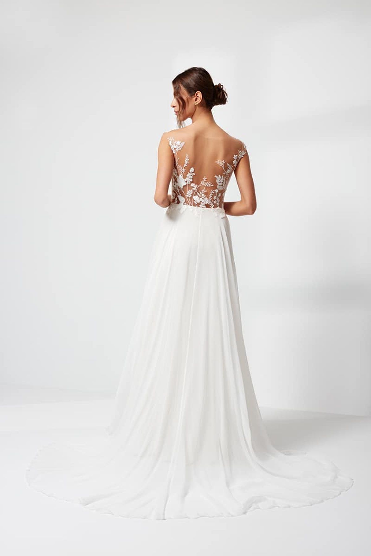 Der Rücken einer Frau, die ein weißes Brautkleid mit Spitzenoberteil trägt.