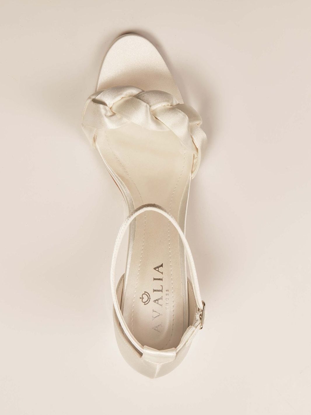 Eine Nahaufnahme eines Paars weißer Sandalen auf einer weißen Oberfläche.