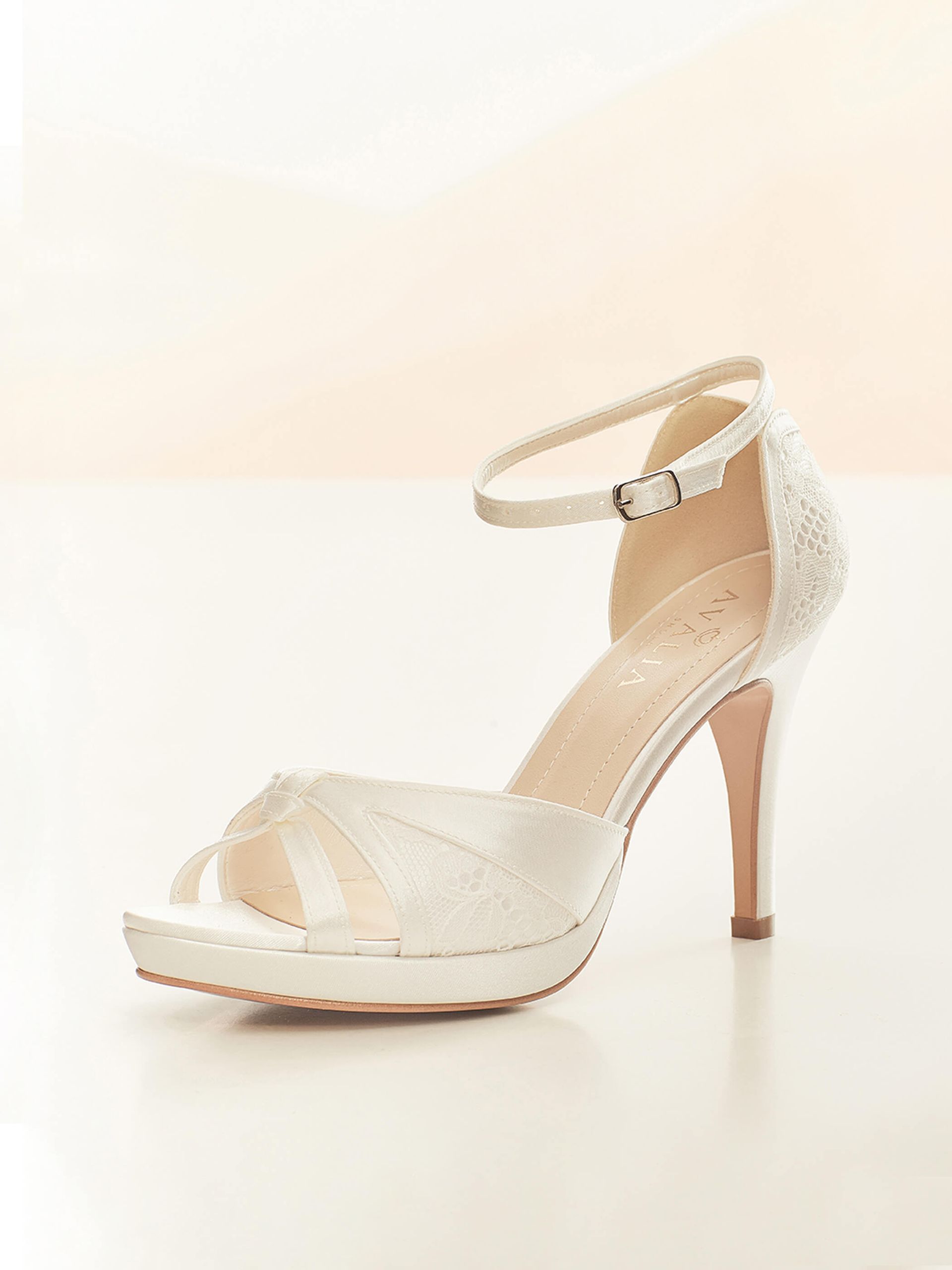 Ein Paar weiße Brautschuhe auf einer weißen Fläche.