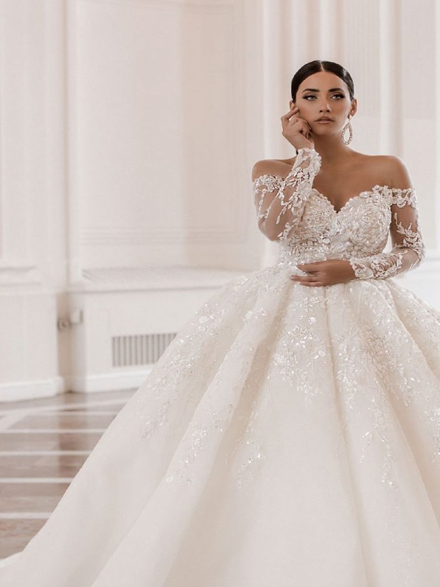 Eine Frau in einem weißen Brautkleid steht in einem Raum.