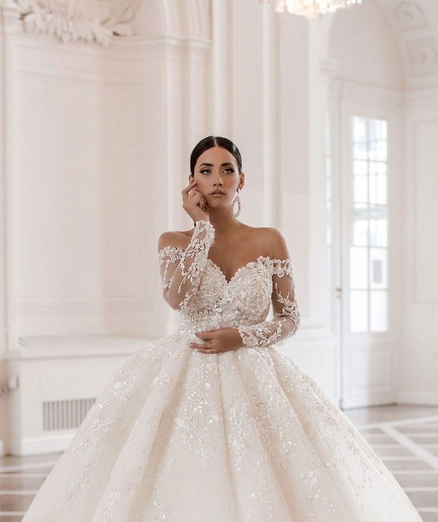 Eine Frau trägt ein weißes Brautkleid mit langen Ärmeln.