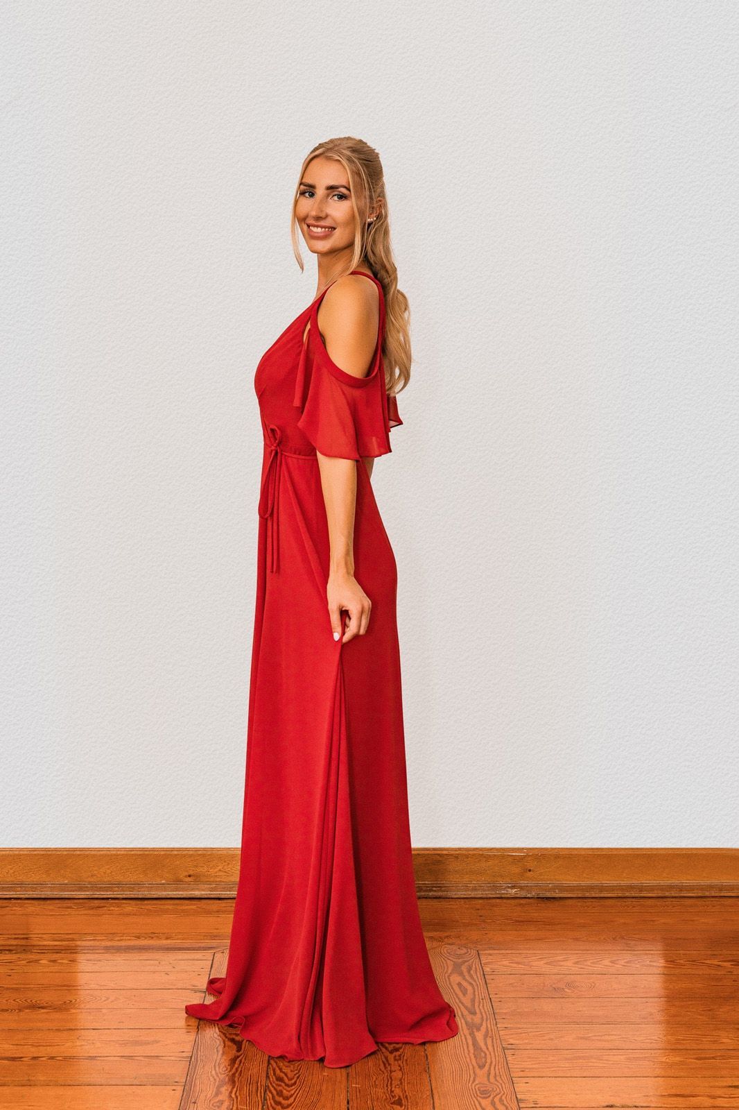 Eine Frau in einem roten Kleid steht auf einem Holzboden.