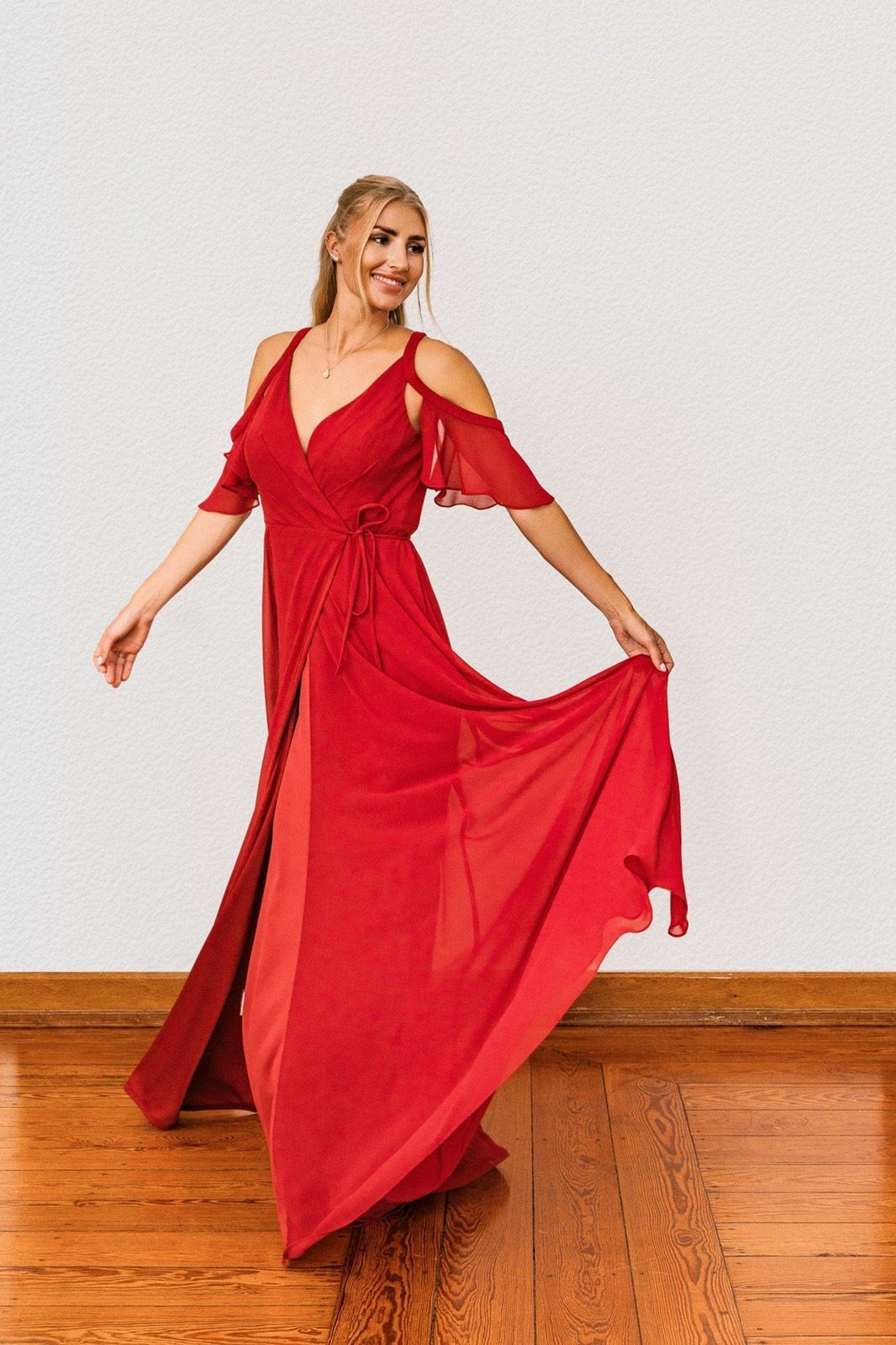 Eine Frau in einem roten Kleid tanzt auf einem Holzboden.