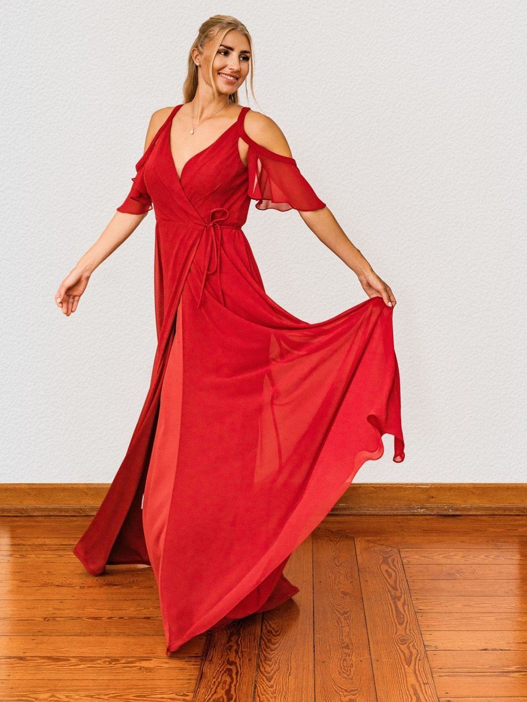 Eine Frau in einem roten Kleid tanzt auf einem Holzboden.