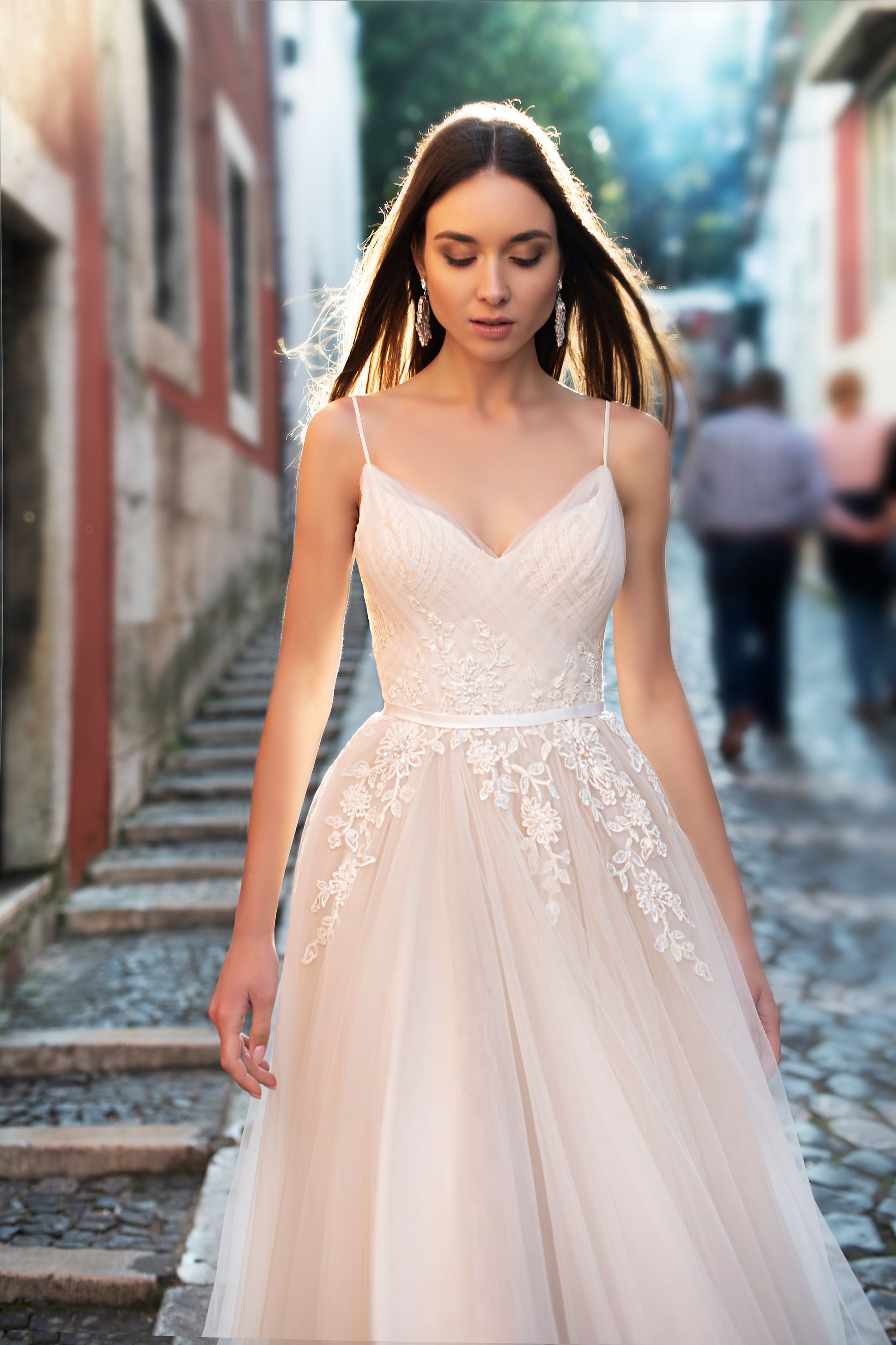 Eine Frau in einem weißen Kleid steht vor Blumen.