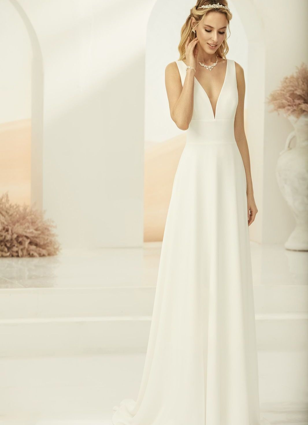 Eine Frau in einem weißen Brautkleid hält einen Blumenstrauß.