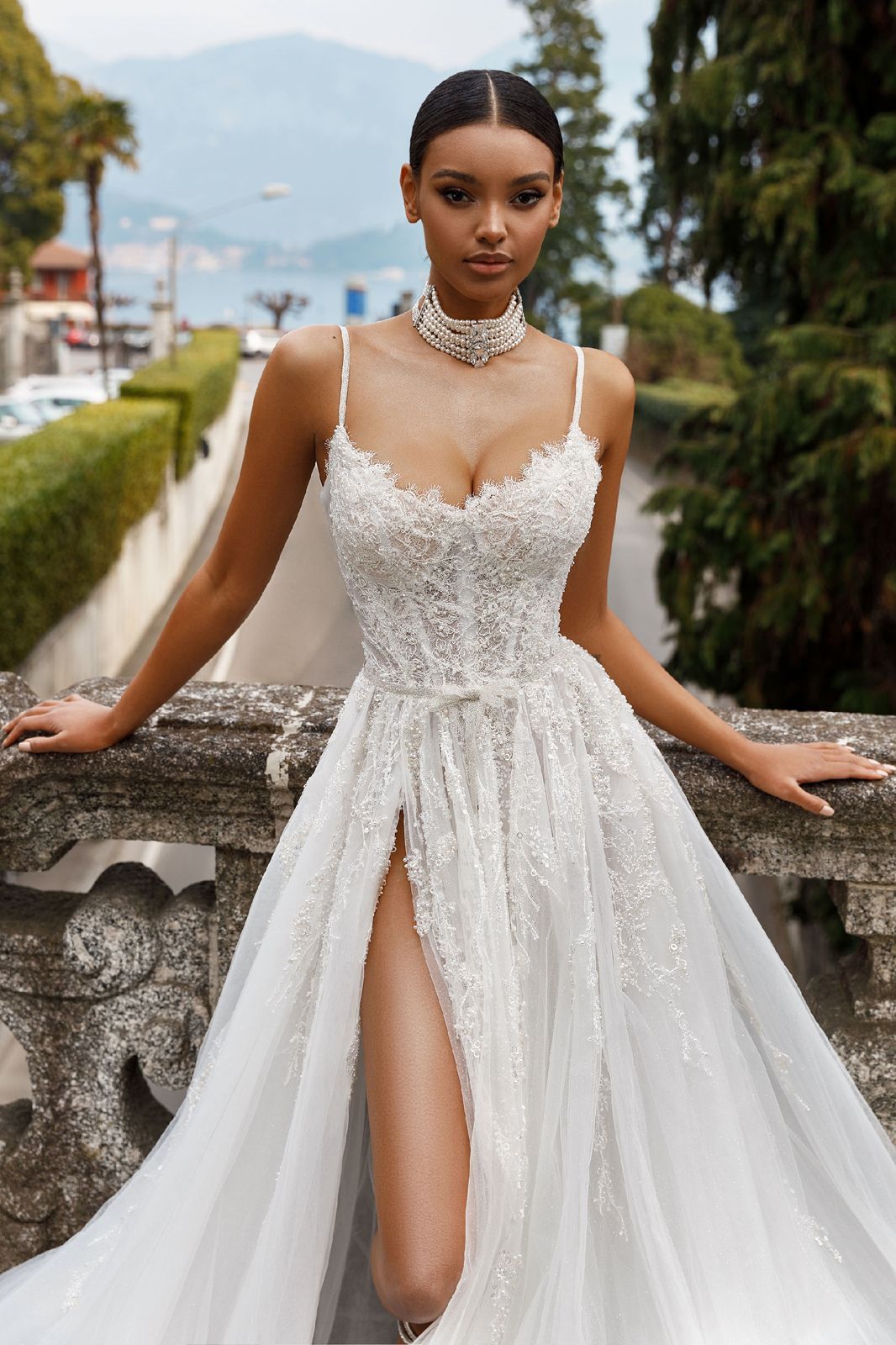 Eine Frau in einem weißen Kleid steht vor Blumen.