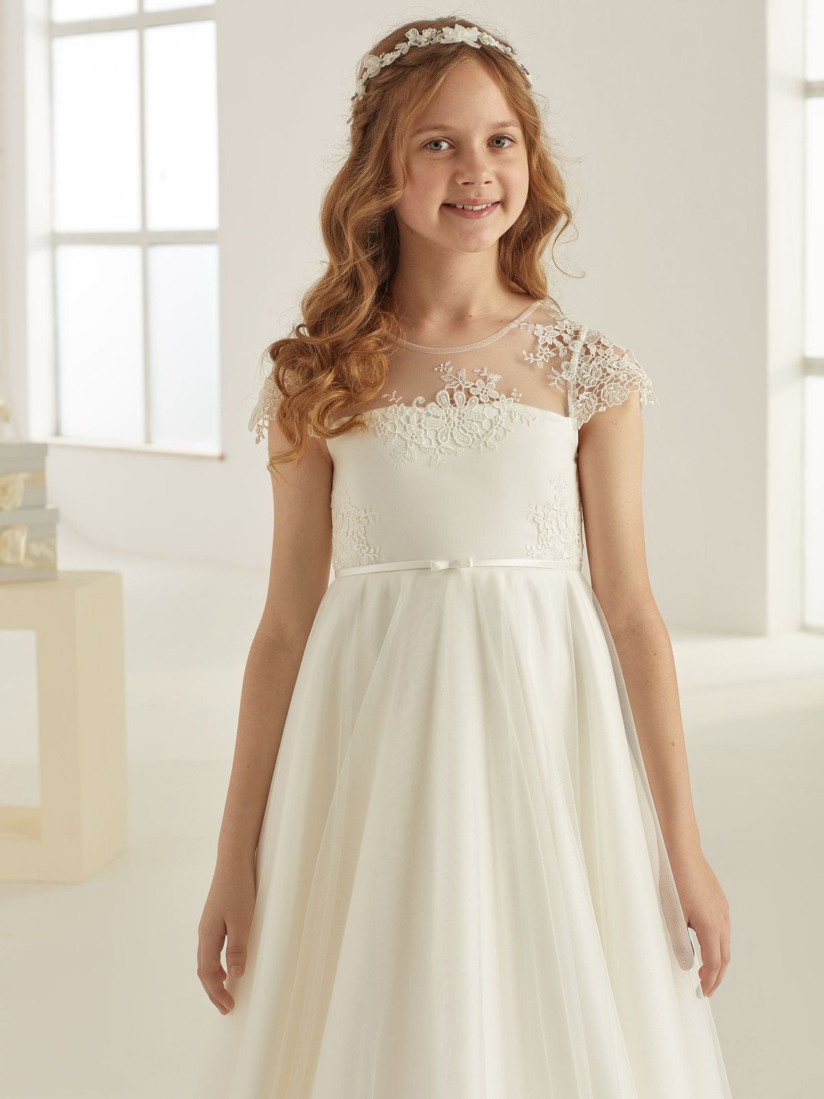 Ein kleines Mädchen trägt ein weißes Kleid und ein Stirnband.