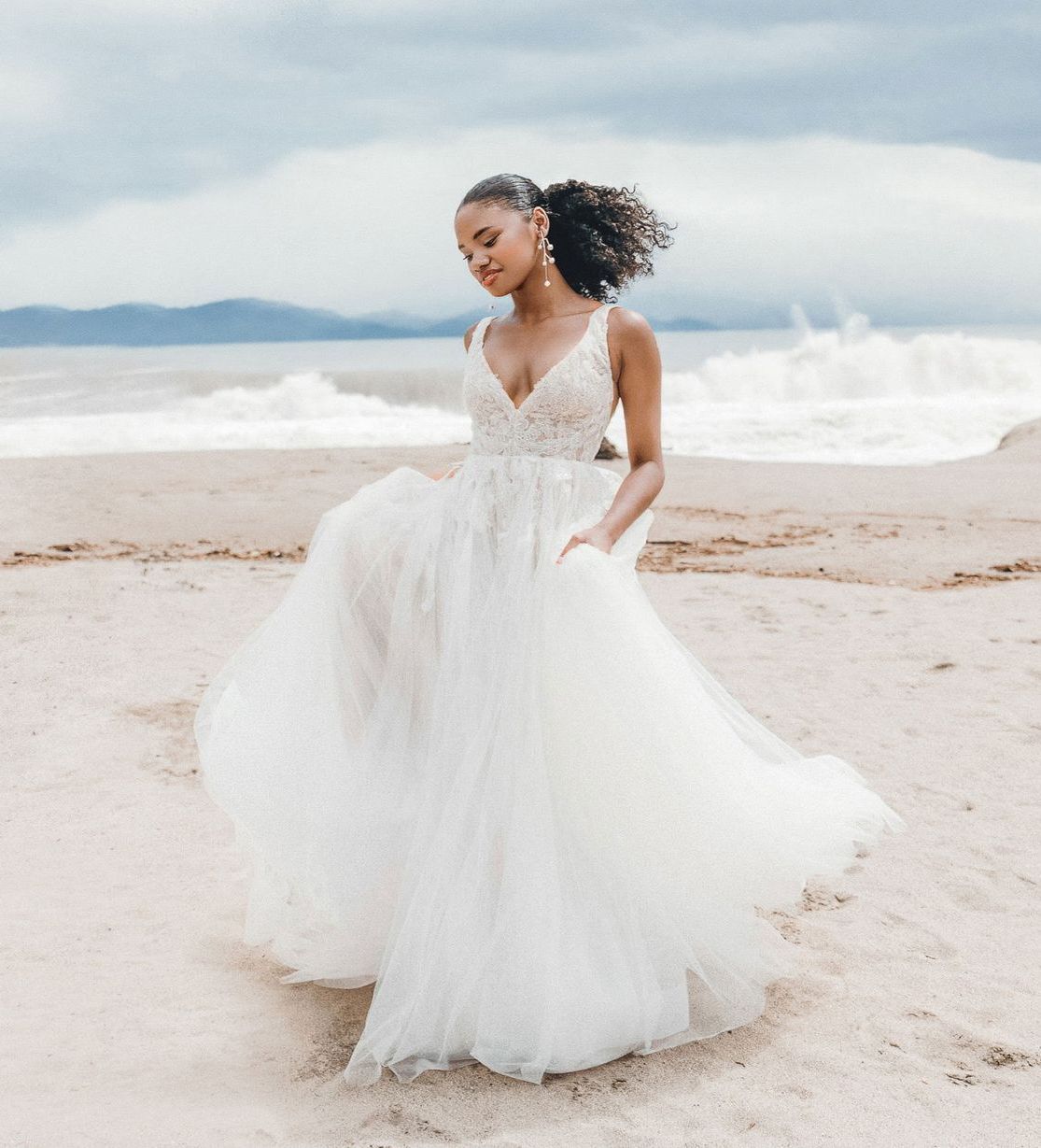 Eine Frau in einem weißen Kleid steht vor Blumen.