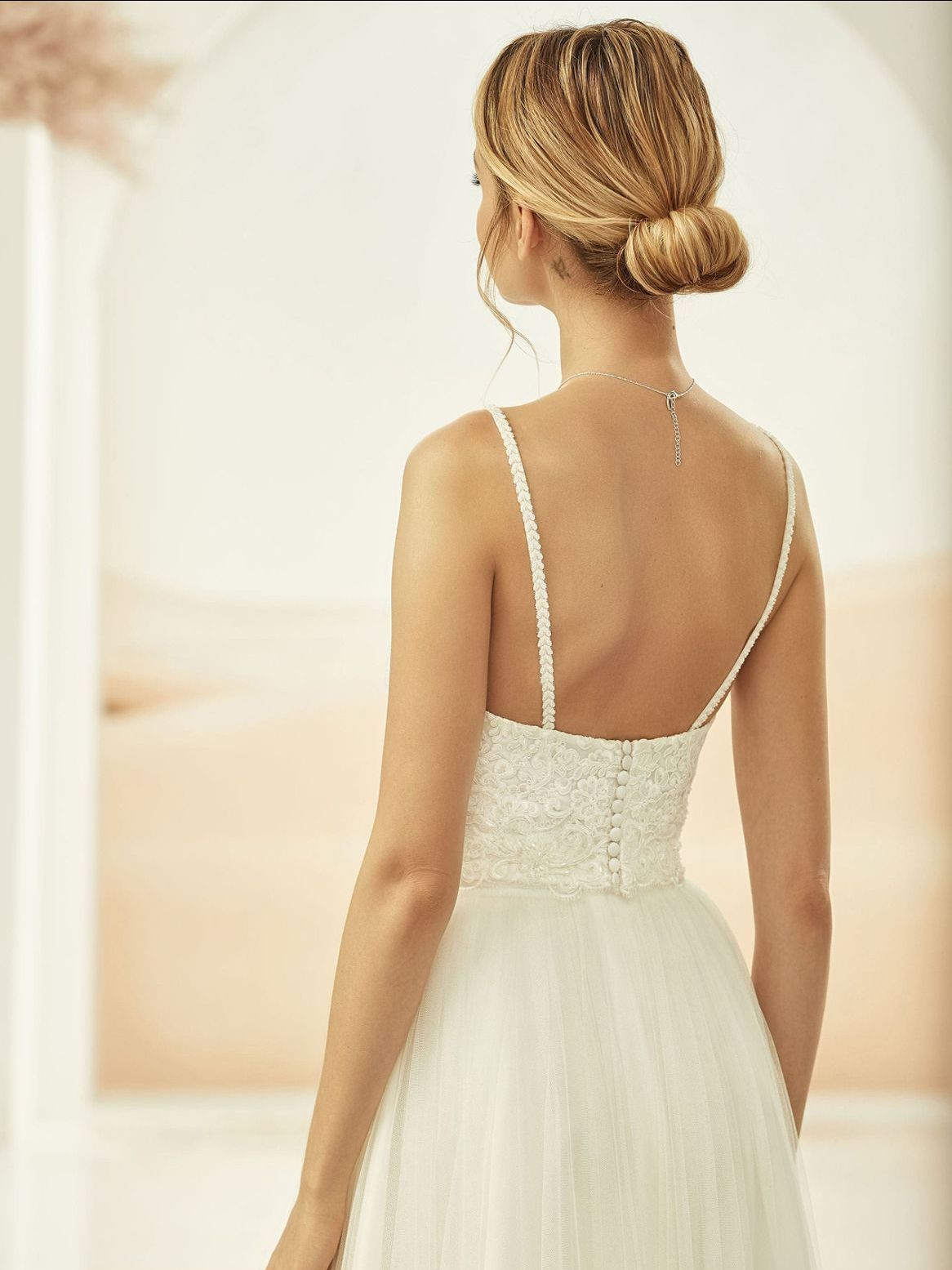 Der Rücken einer Frau in einem weißen Hochzeitskleid.