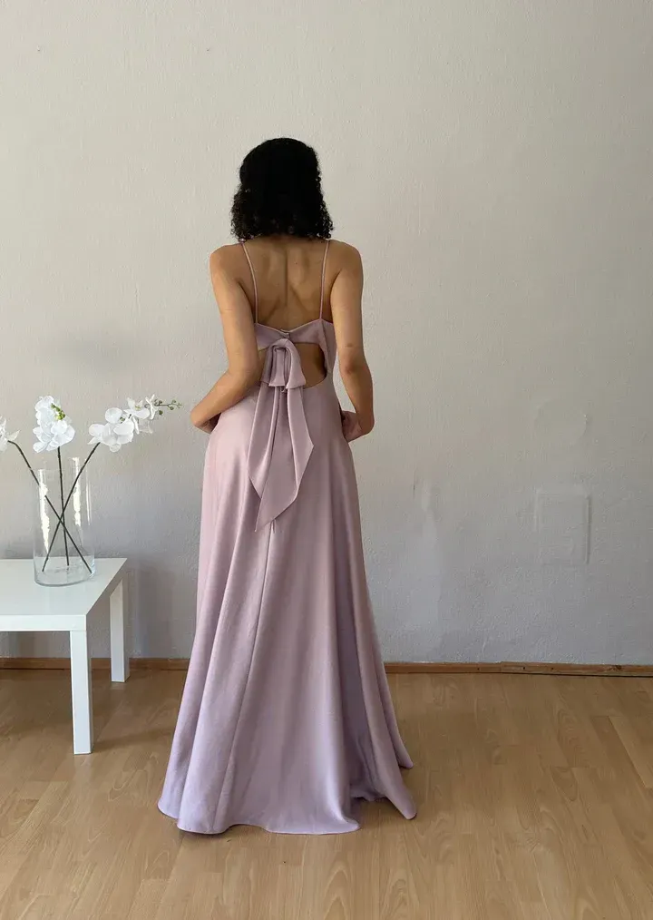 Eine Frau in einem langen lila Kleid steht in einem Raum.