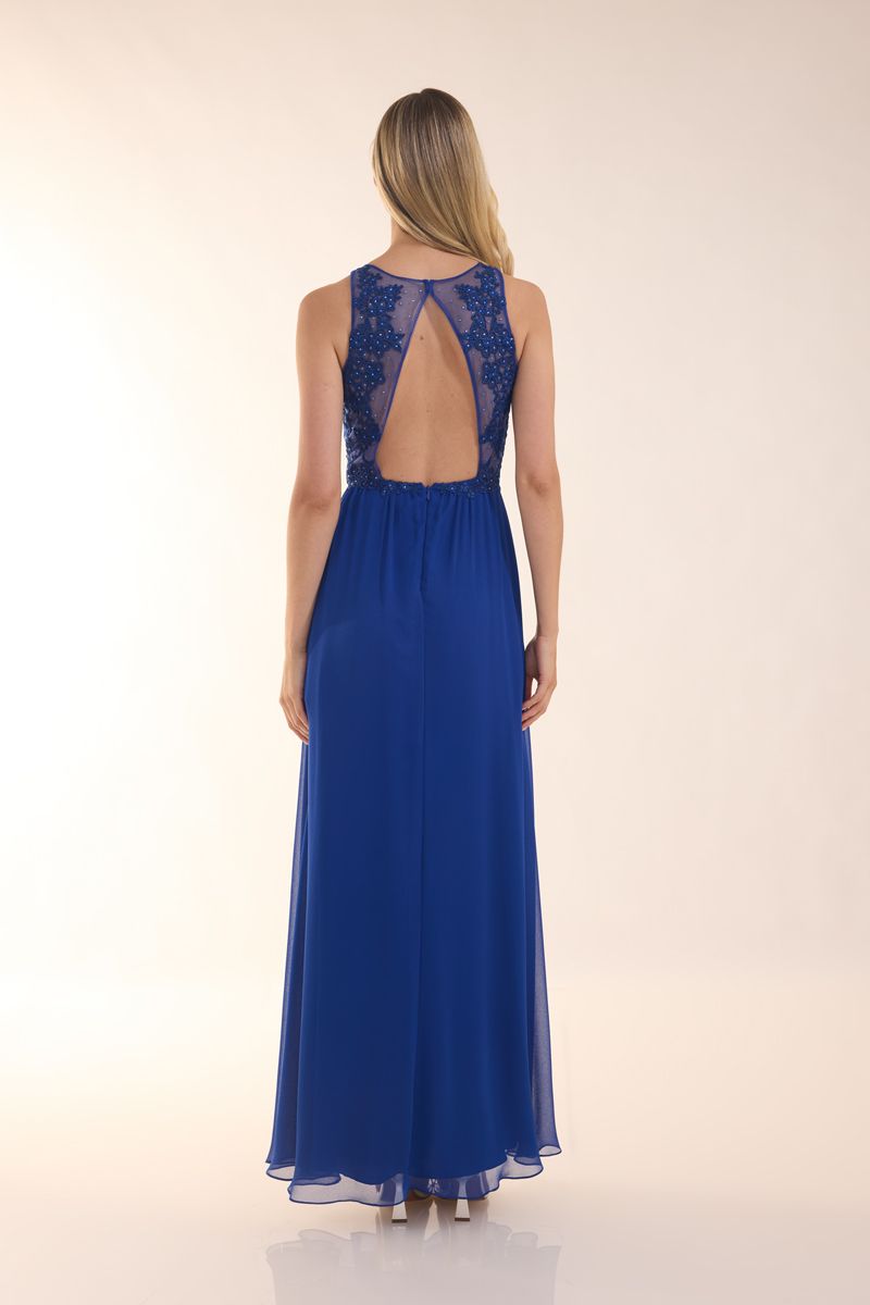 Eine Frau in einem grünen Kleid steht vor einer Holztür.