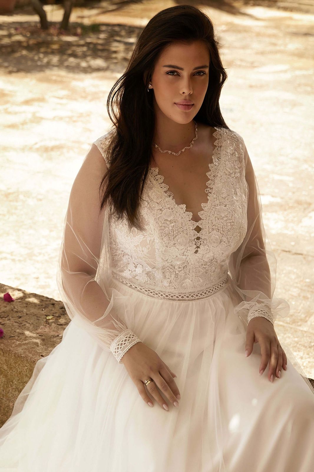 Eine Frau in einem weißen Kleid und einem Strohhut steht am Strand.