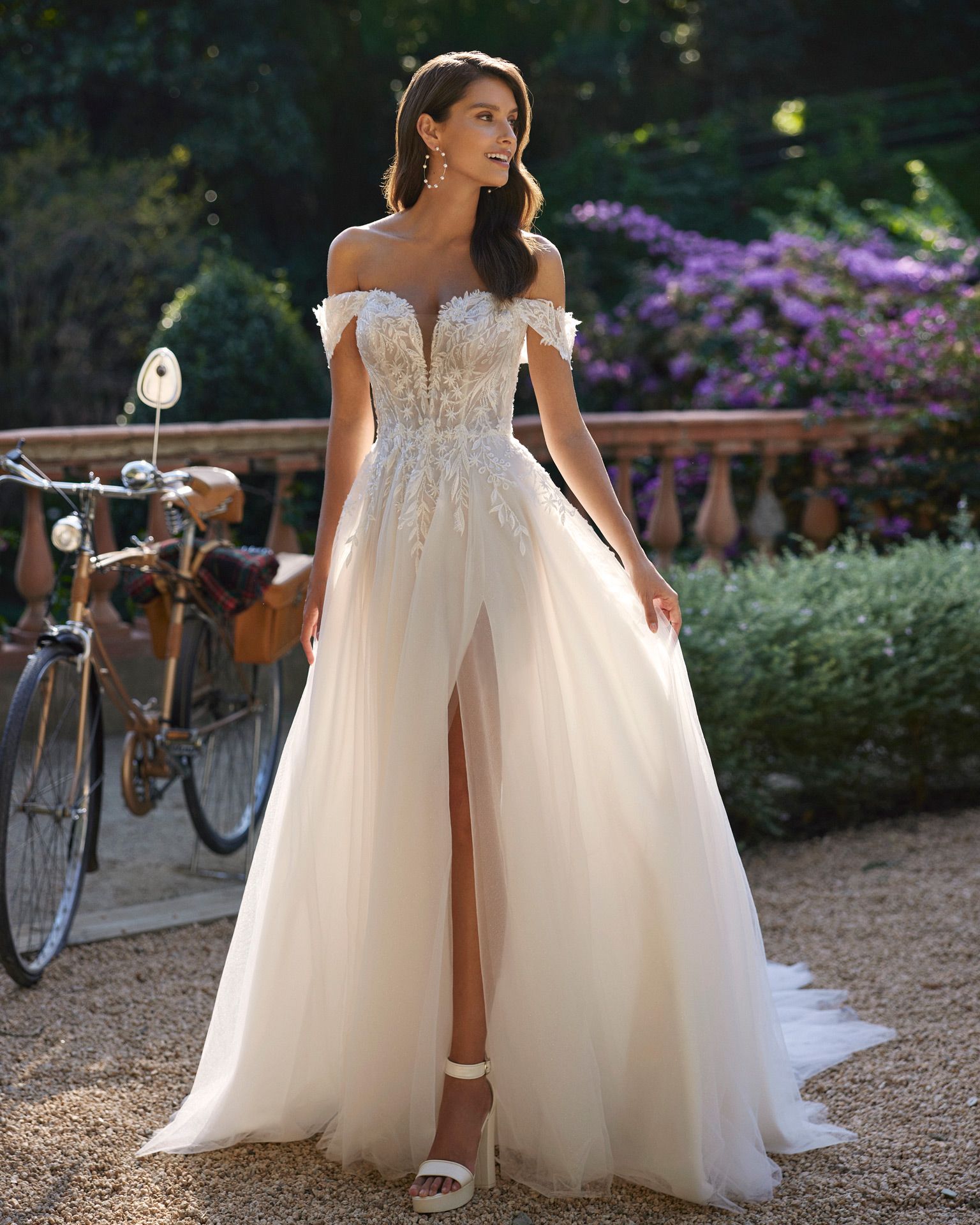 Eine Frau in einem weißen Brautkleid steht neben einem Fahrrad.