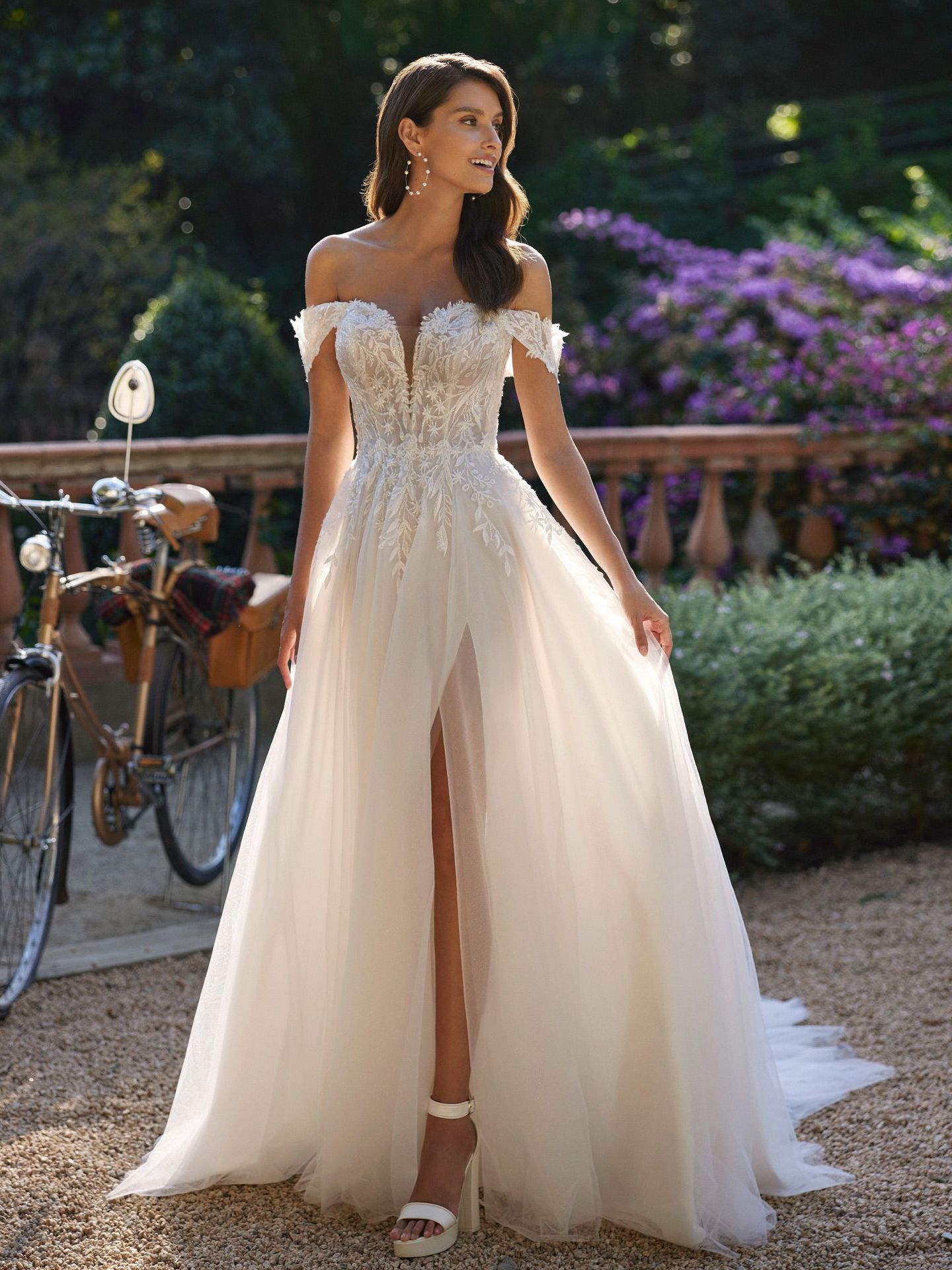 Eine Frau in einem weißen Brautkleid steht neben einem Fahrrad.
