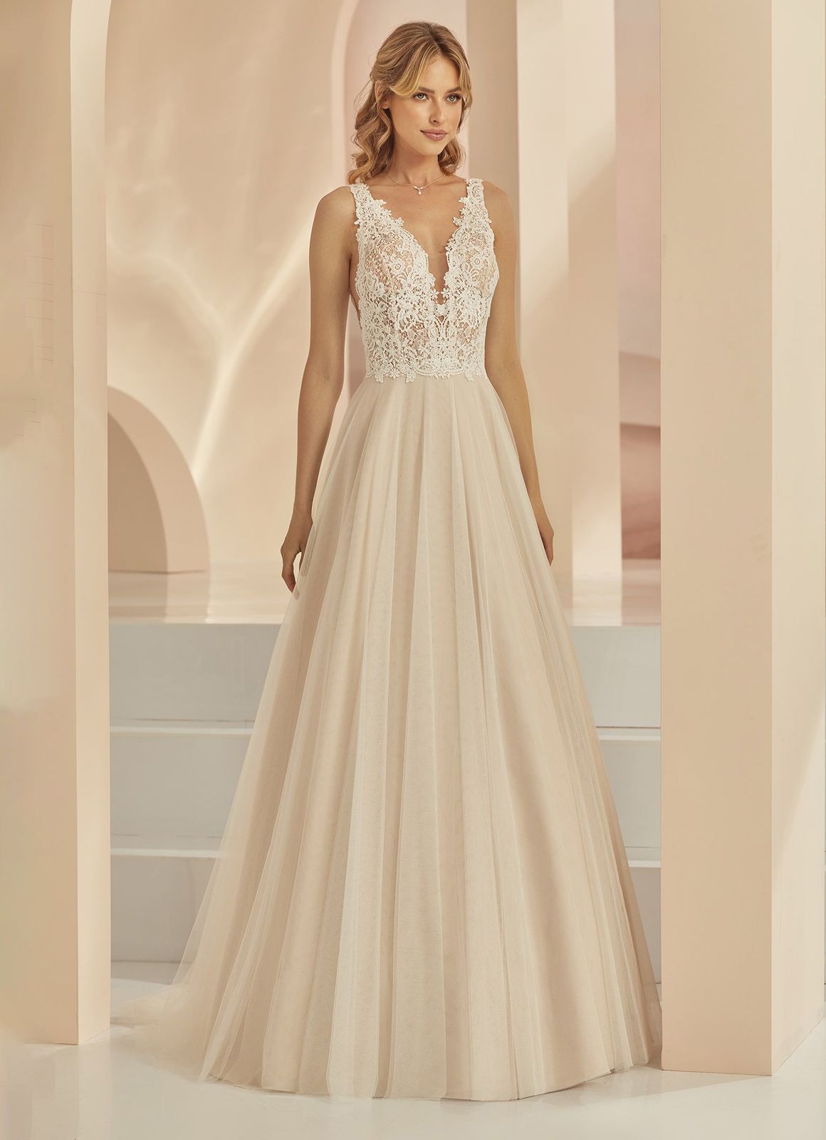 Eine Frau in einem weißen Brautkleid steht vor lila Blumen.