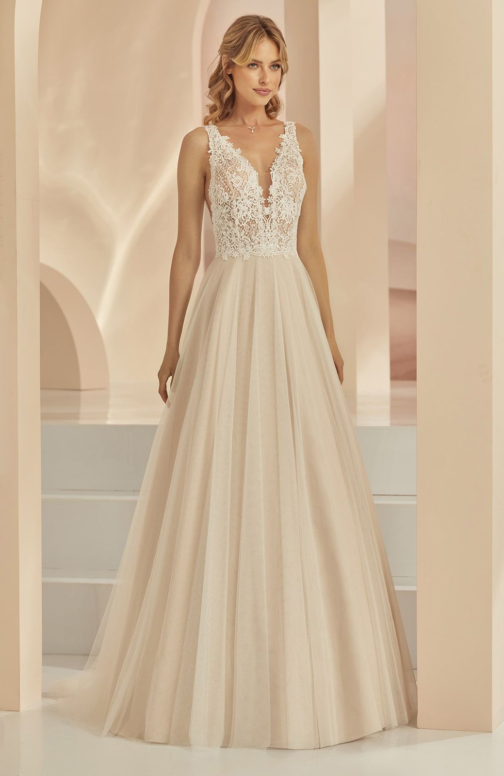 Eine Frau in einem weißen Brautkleid steht vor lila Blumen.
