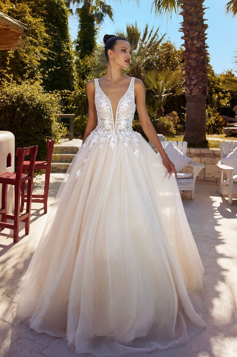 Eine Frau in einem weißen Brautkleid steht vor lila Blumen.