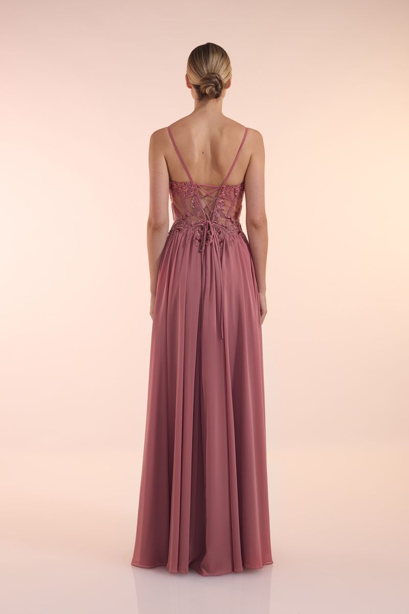 Eine Frau in einem grünen Kleid steht vor einer Holztür.