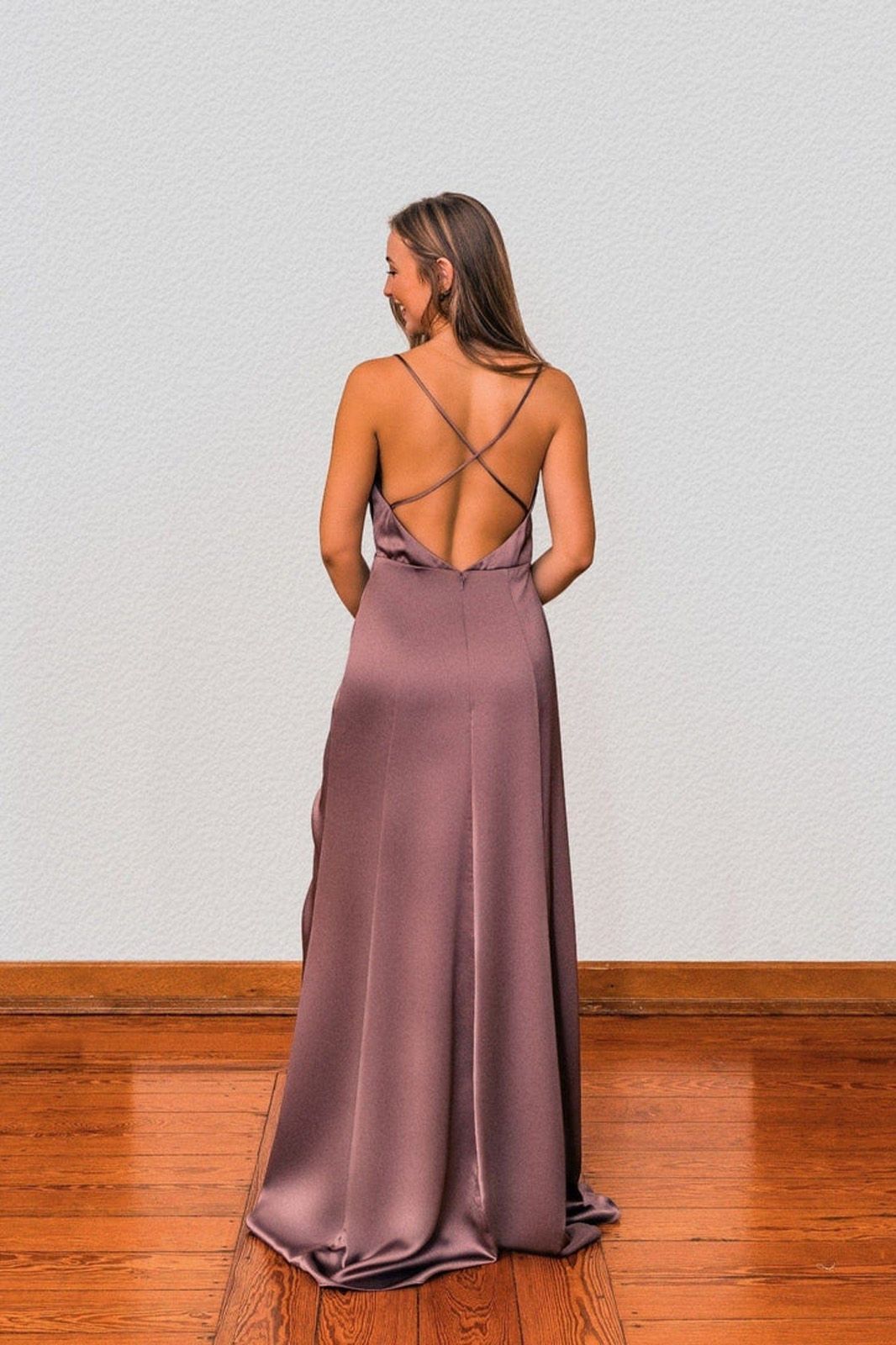 Eine Frau in einem langen lila Kleid steht auf einem Holzboden.