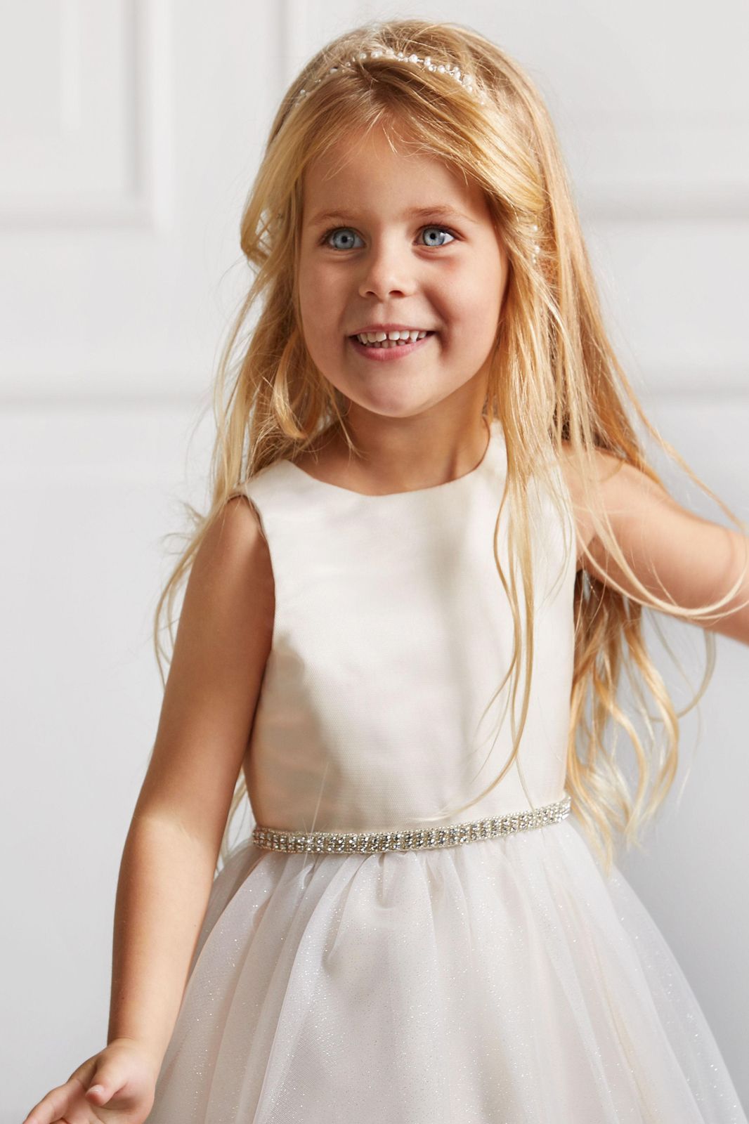 Ein kleines Mädchen trägt ein weißes Kleid und ein Stirnband.