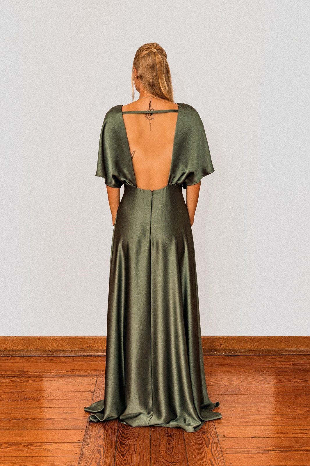 Eine Frau in einem grünen Kleid steht auf einem Holzboden.