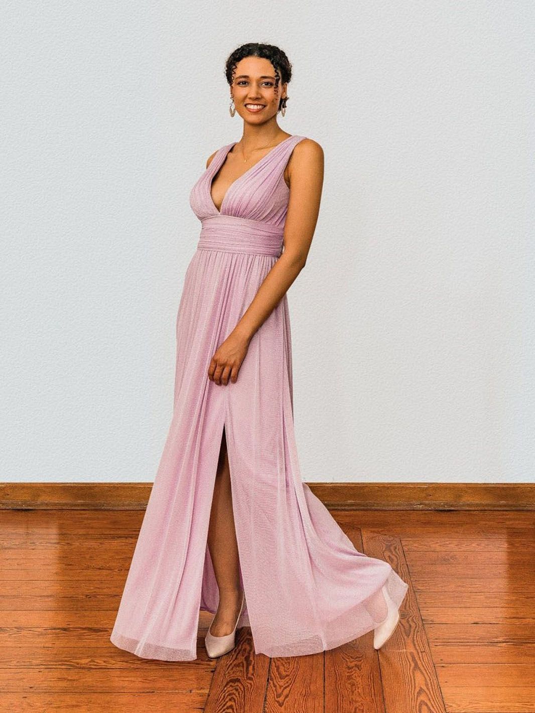 Eine Frau in einem langen lila Kleid steht auf einem Holzboden.