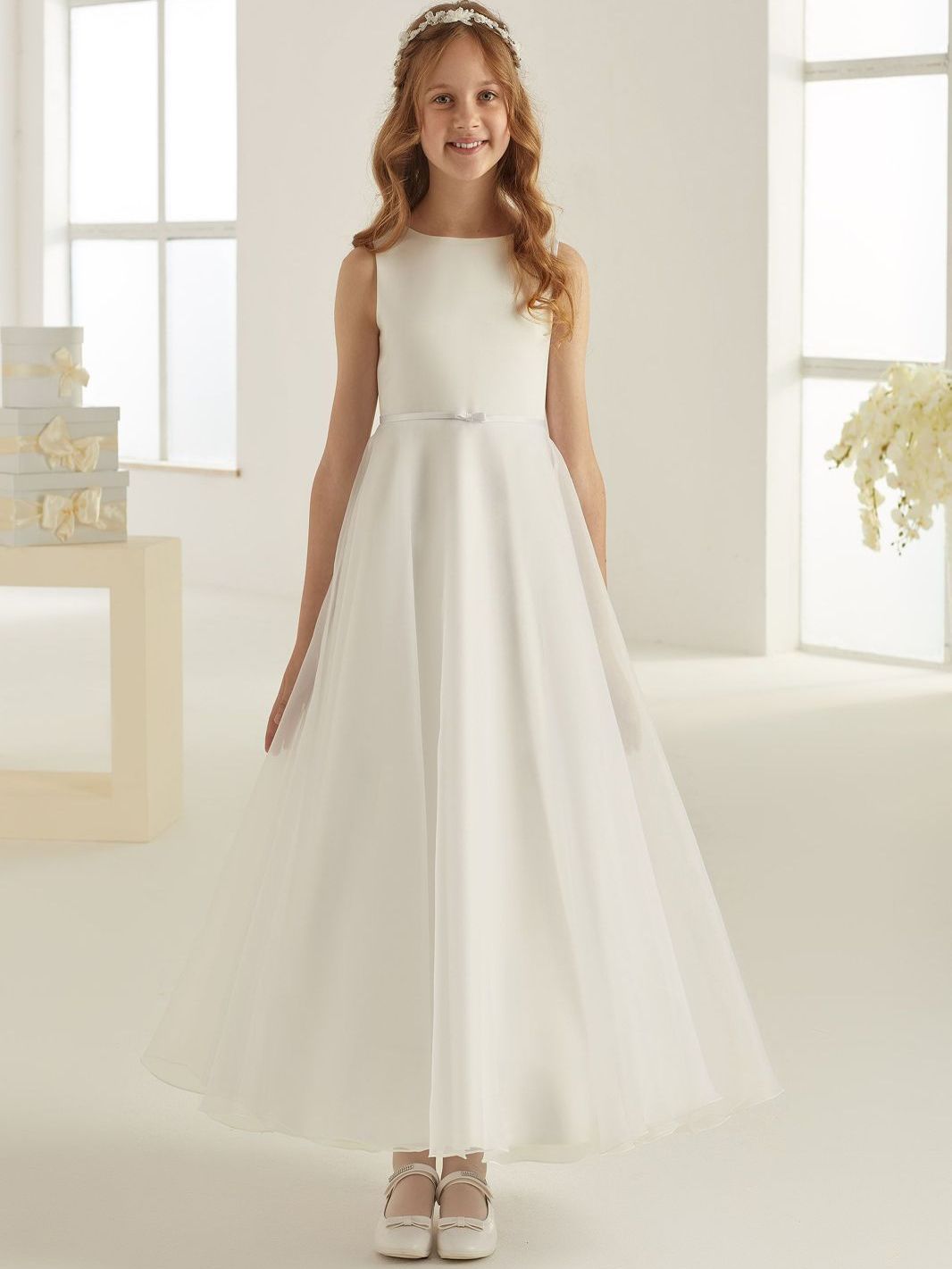 Ein kleines Mädchen trägt ein weißes Blumenmädchenkleid.
