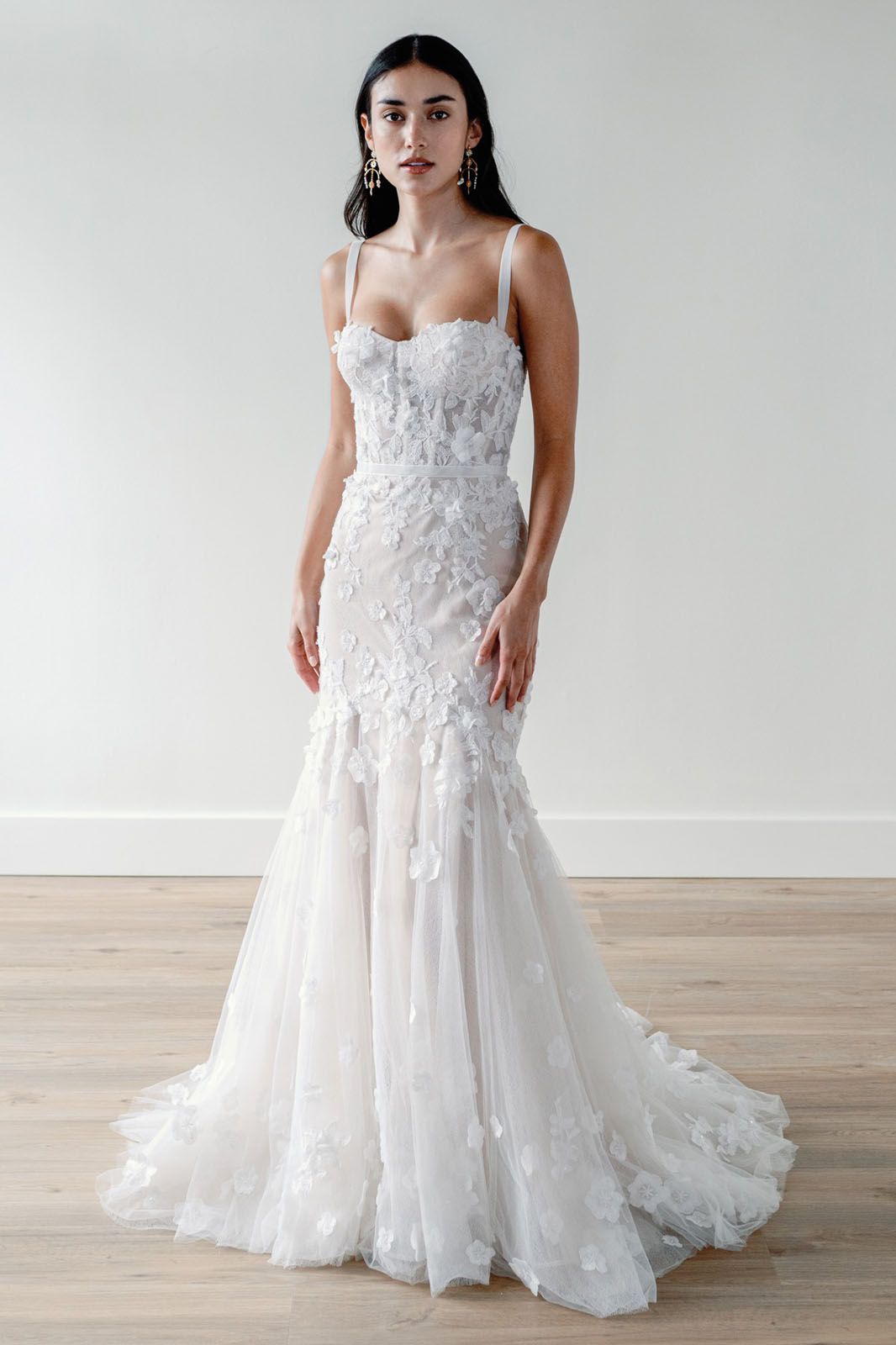 Eine Frau in einem Brautkleid steht an einem steinigen Strand.