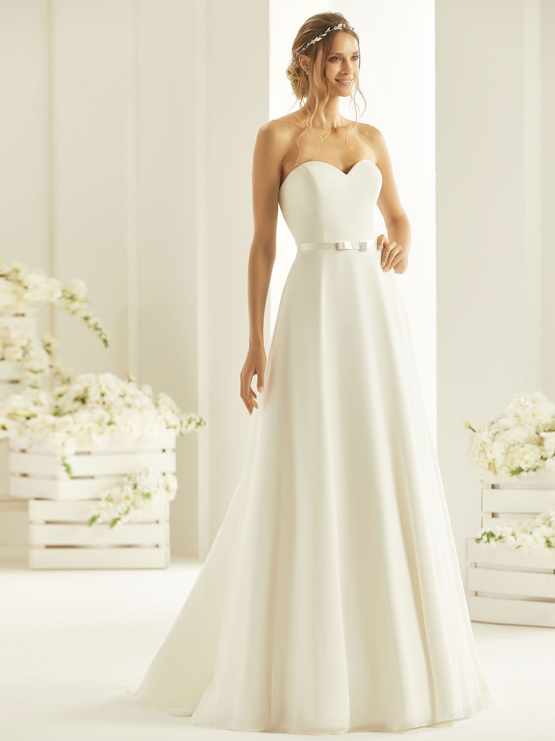 Eine Frau in einem weißen Brautkleid hält einen Blumenstrauß.
