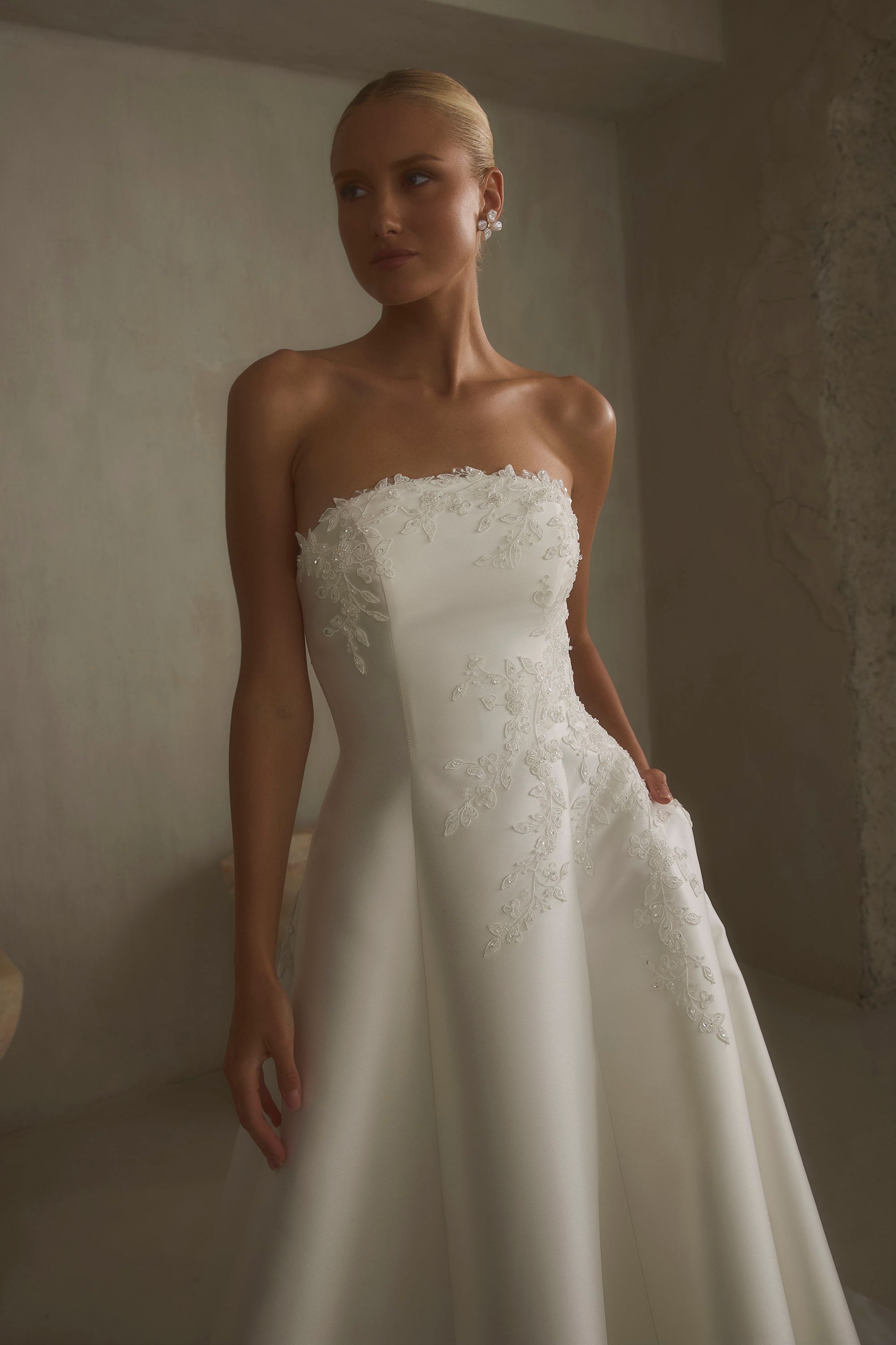 Eine Frau in einem Brautkleid steht an einem steinigen Strand.