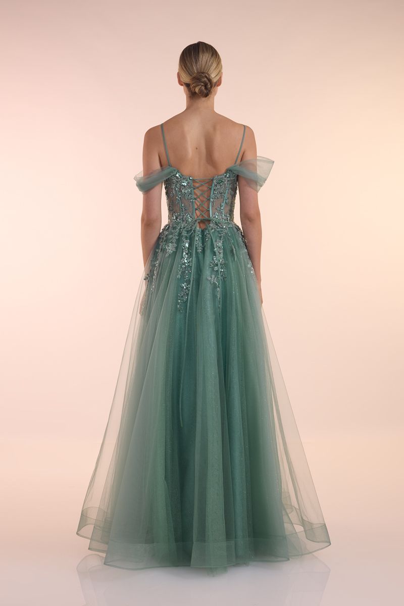 Eine Frau in einem grünen Kleid steht vor einer Holztür.
