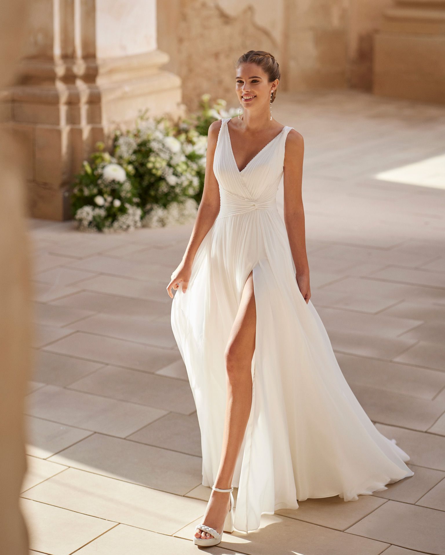 Eine Frau in einem weißen Brautkleid hält einen Blumenstrauß.