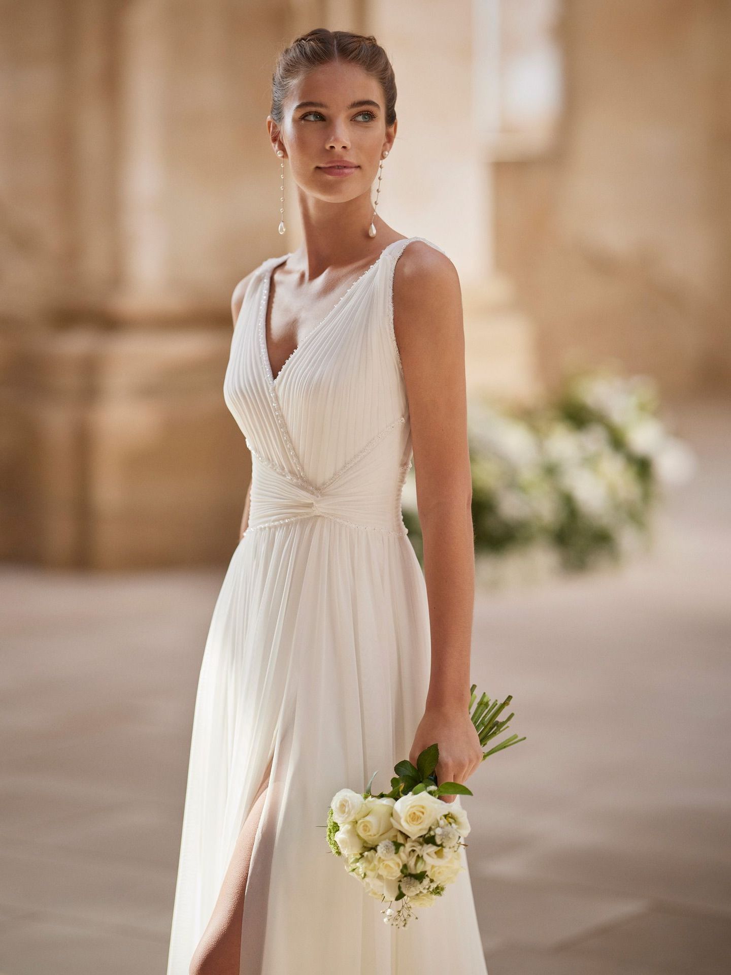 Eine Frau in einem weißen Brautkleid hält einen Blumenstrauß.
