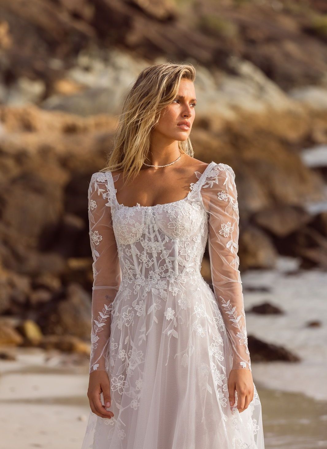 Eine Frau in einem Brautkleid steht in der Wüste.