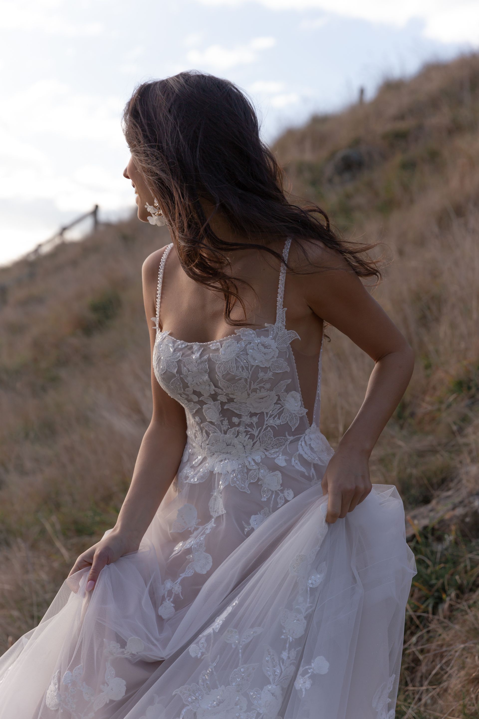 Eine Frau in einem Brautkleid steht an einem steinigen Strand.