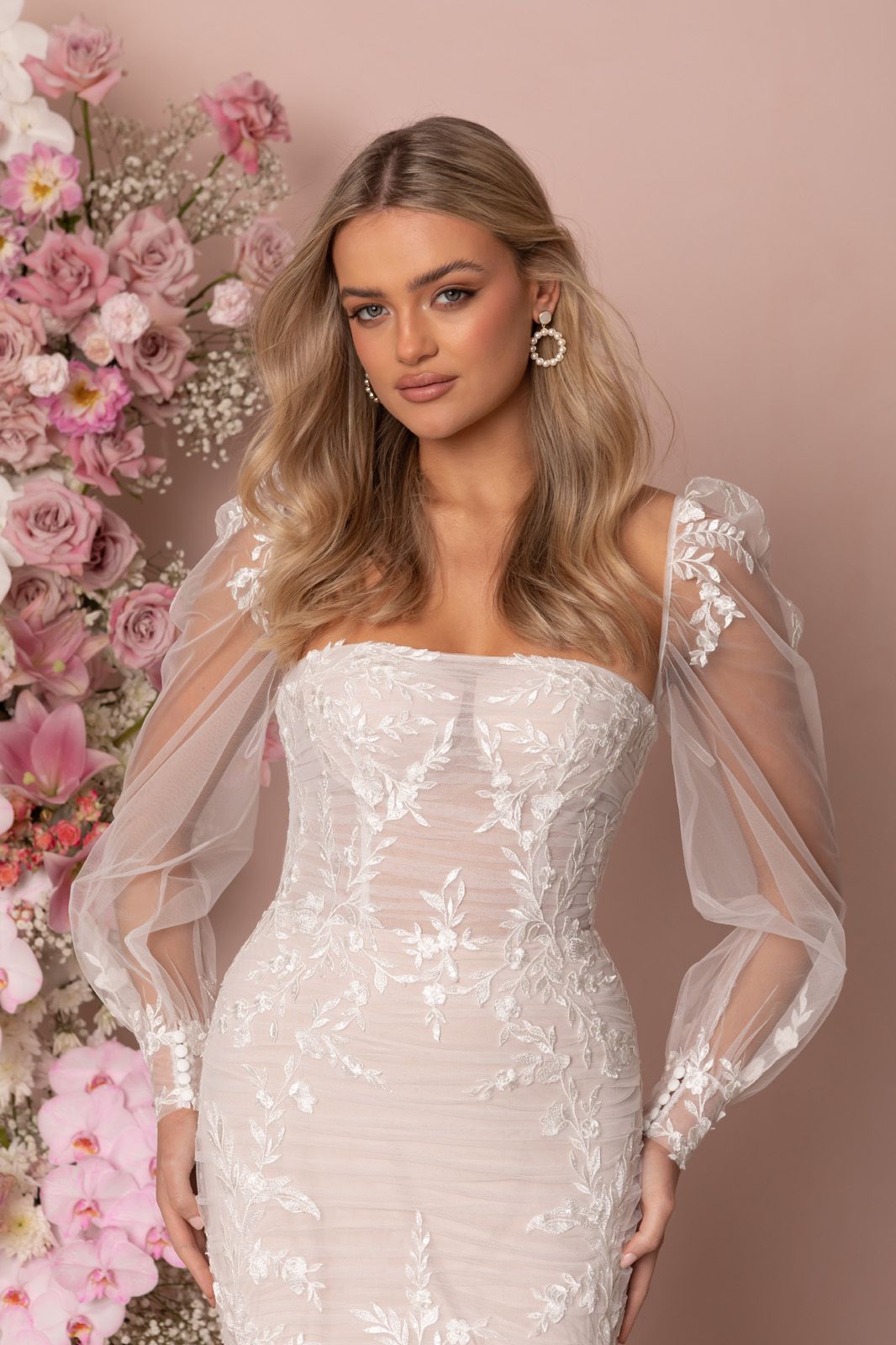 Eine Frau in einem Brautkleid steht an einem steinigen Strand.