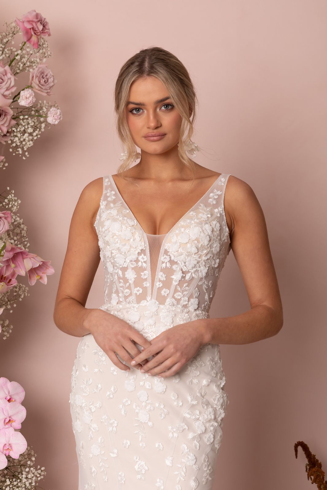 Eine Frau in einem Brautkleid steht an einem steinigen Strand.