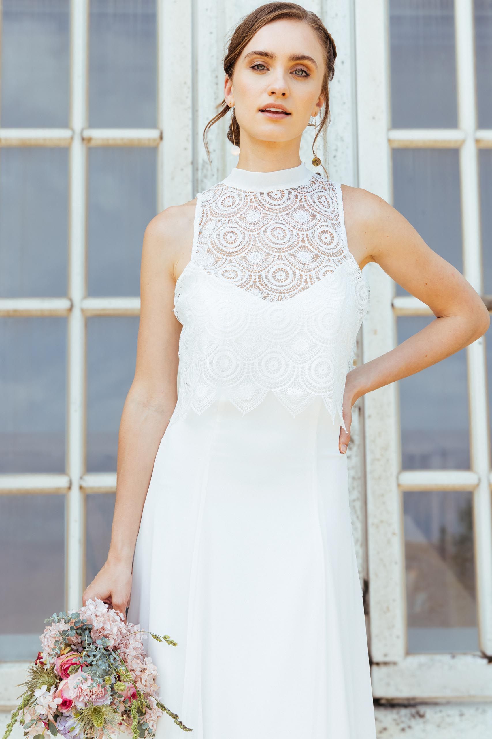 Eine Frau in einem weißen Kleid steht vor Blumen.