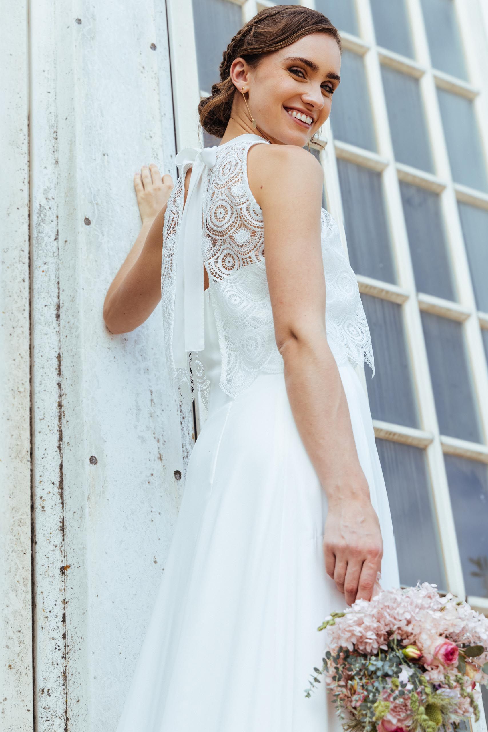 Eine Frau in einem Brautkleid steht auf einer Treppe vor einem Gebäude.