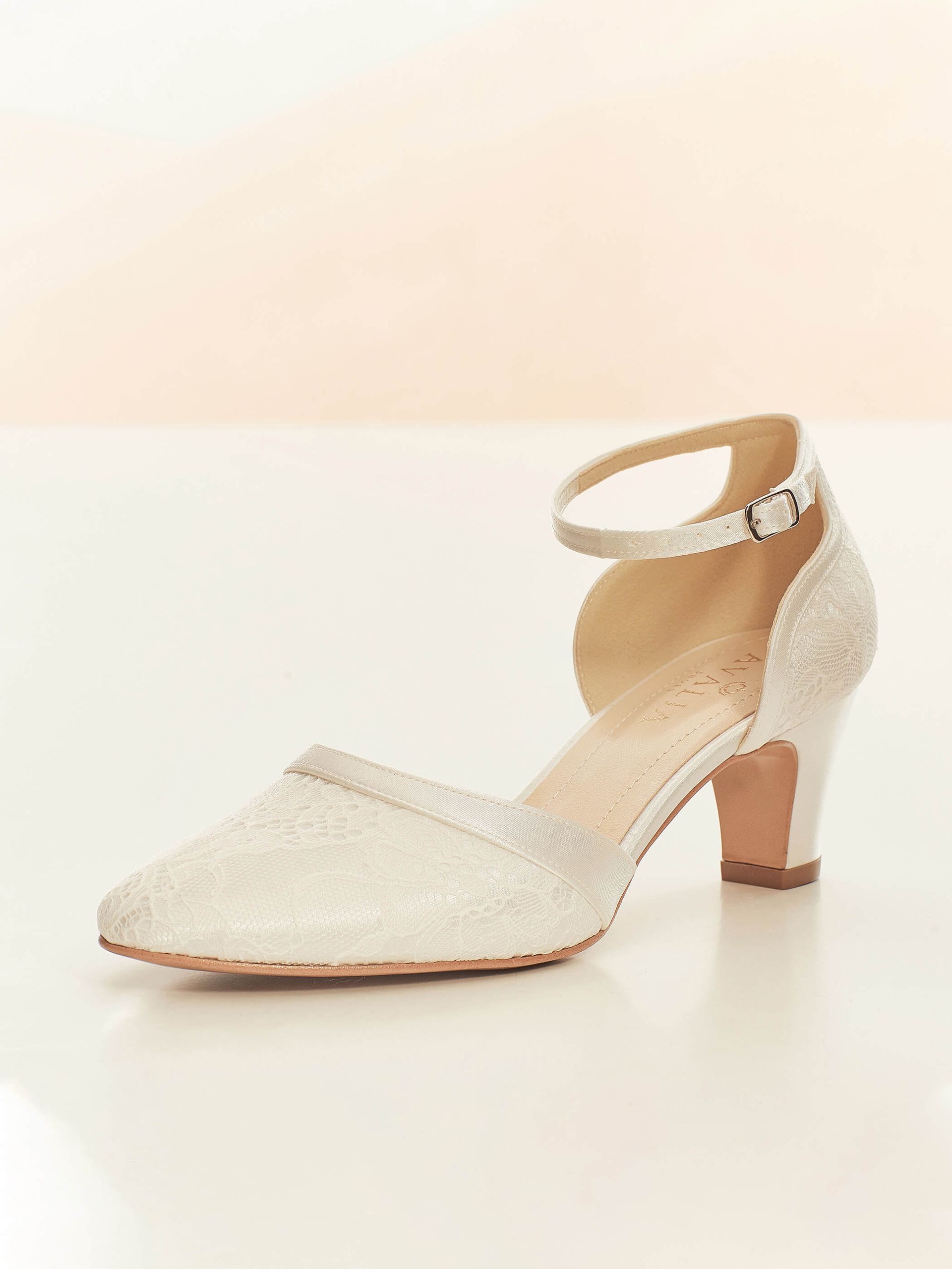 Ein Paar weiße Schuhe mit Knöchelriemen auf einer weißen Fläche.