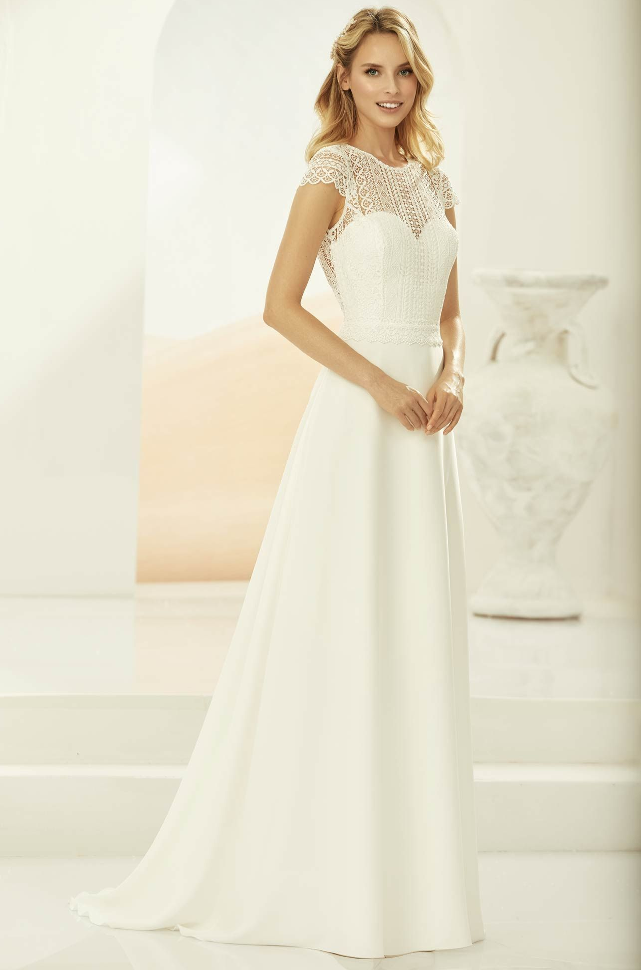 Eine Frau in einem Brautkleid steht vor einem grauen Hintergrund.