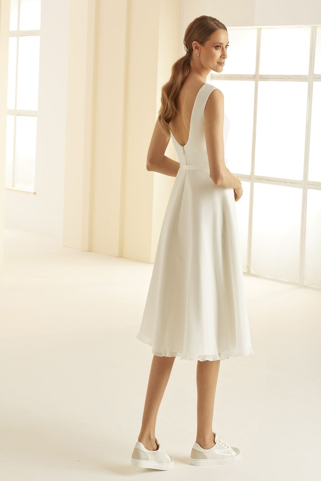 Eine Frau trägt ein weißes Kleid und weiße Turnschuhe.