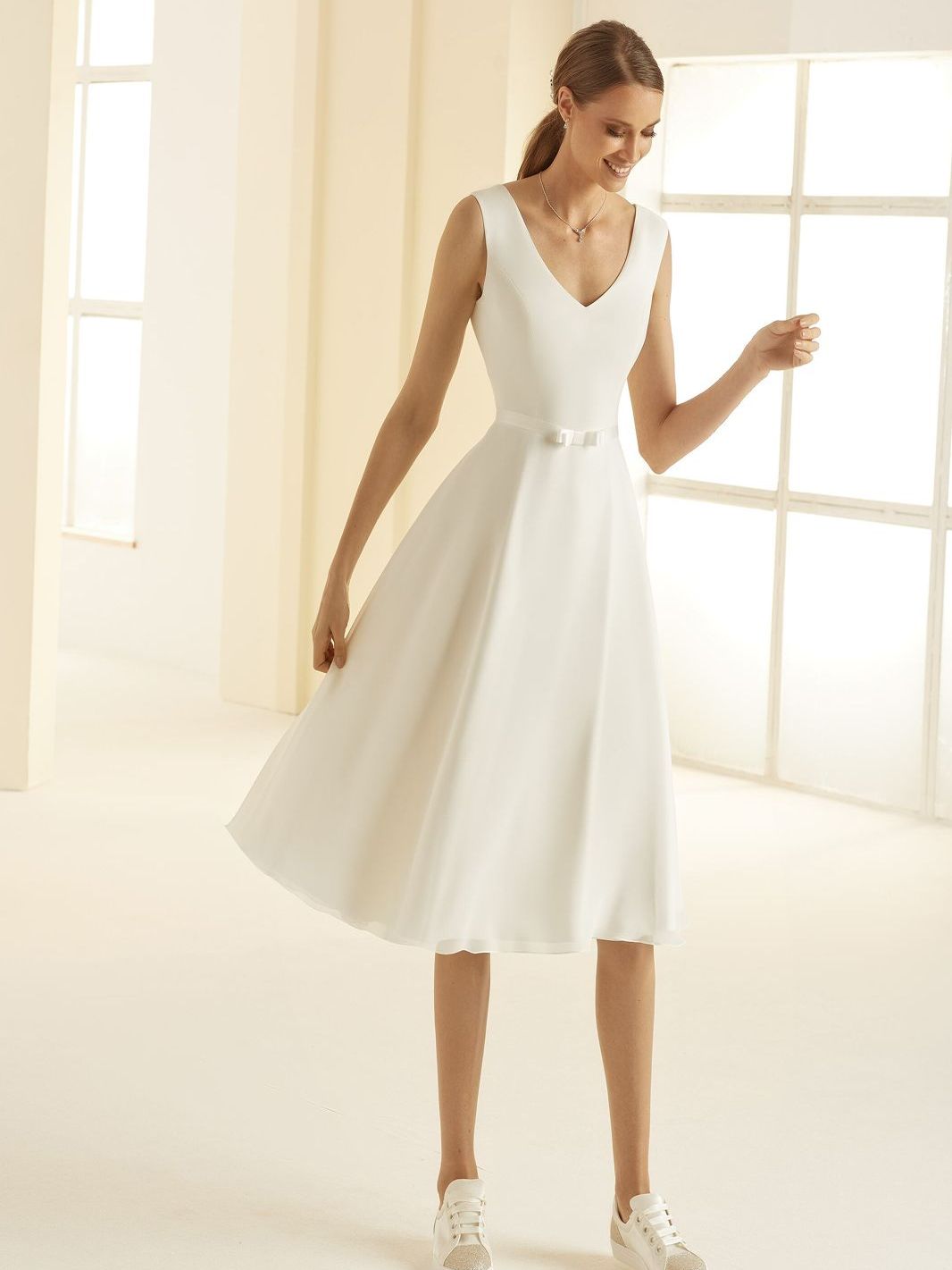 Eine Frau trägt ein weißes Kleid und weiße Turnschuhe.